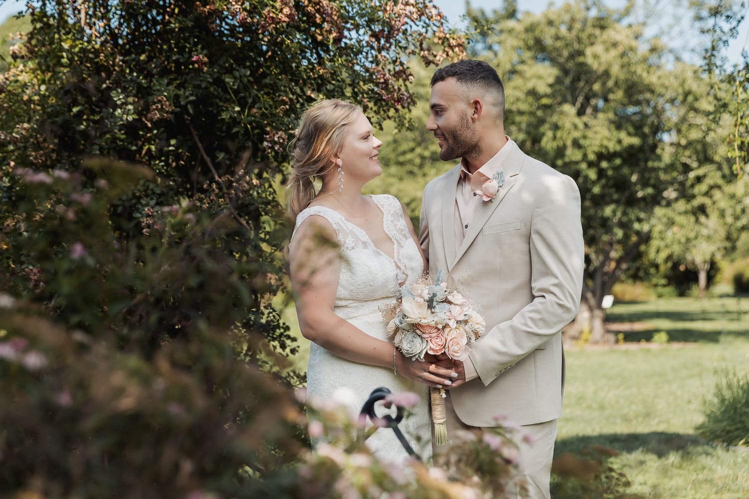 Couple shares an intimate moment on their wedding day in a sunny apple orchard during fall harvest season.