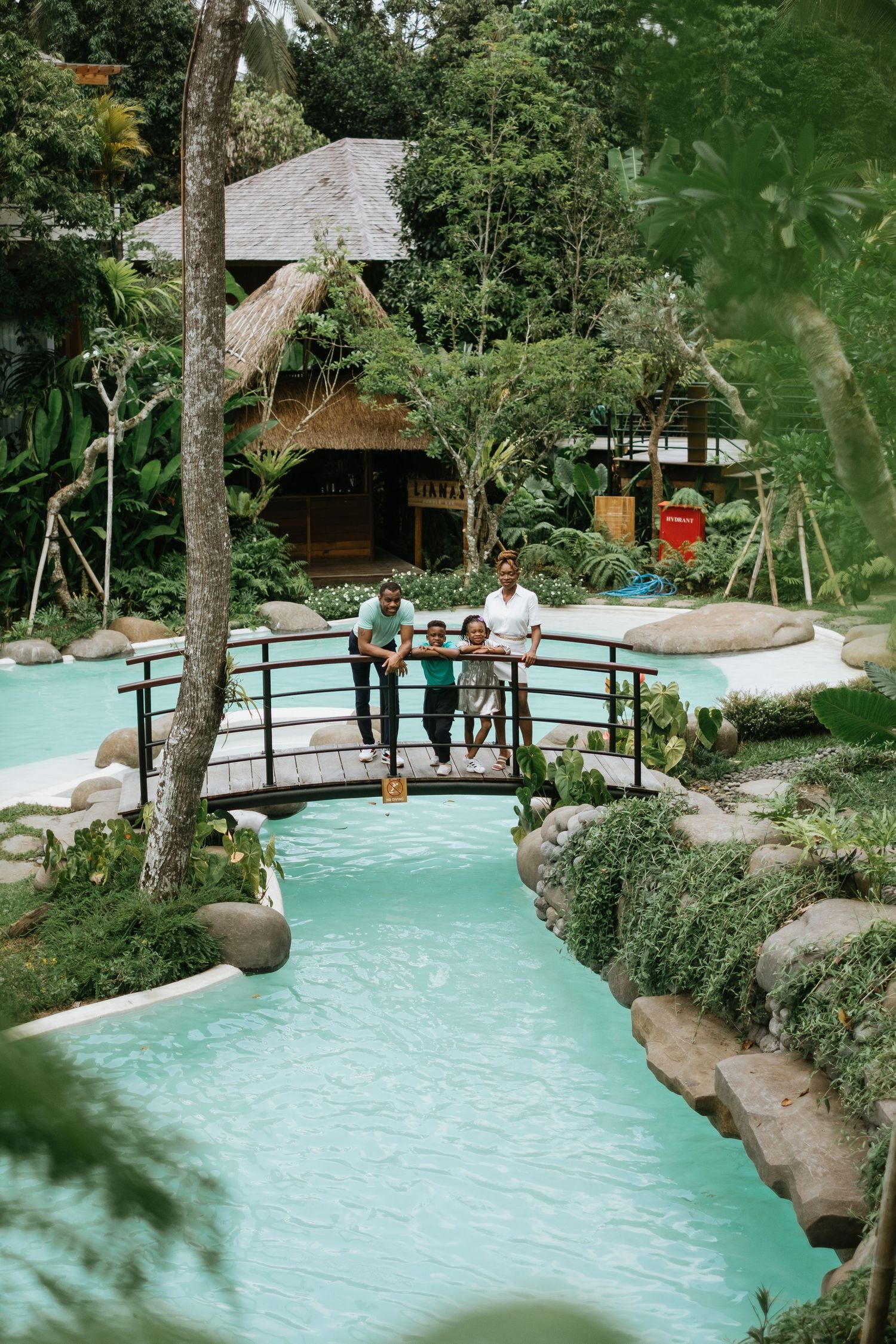Scenic view of a winding pool surrounded by tropical landscaping and wooden walkways.