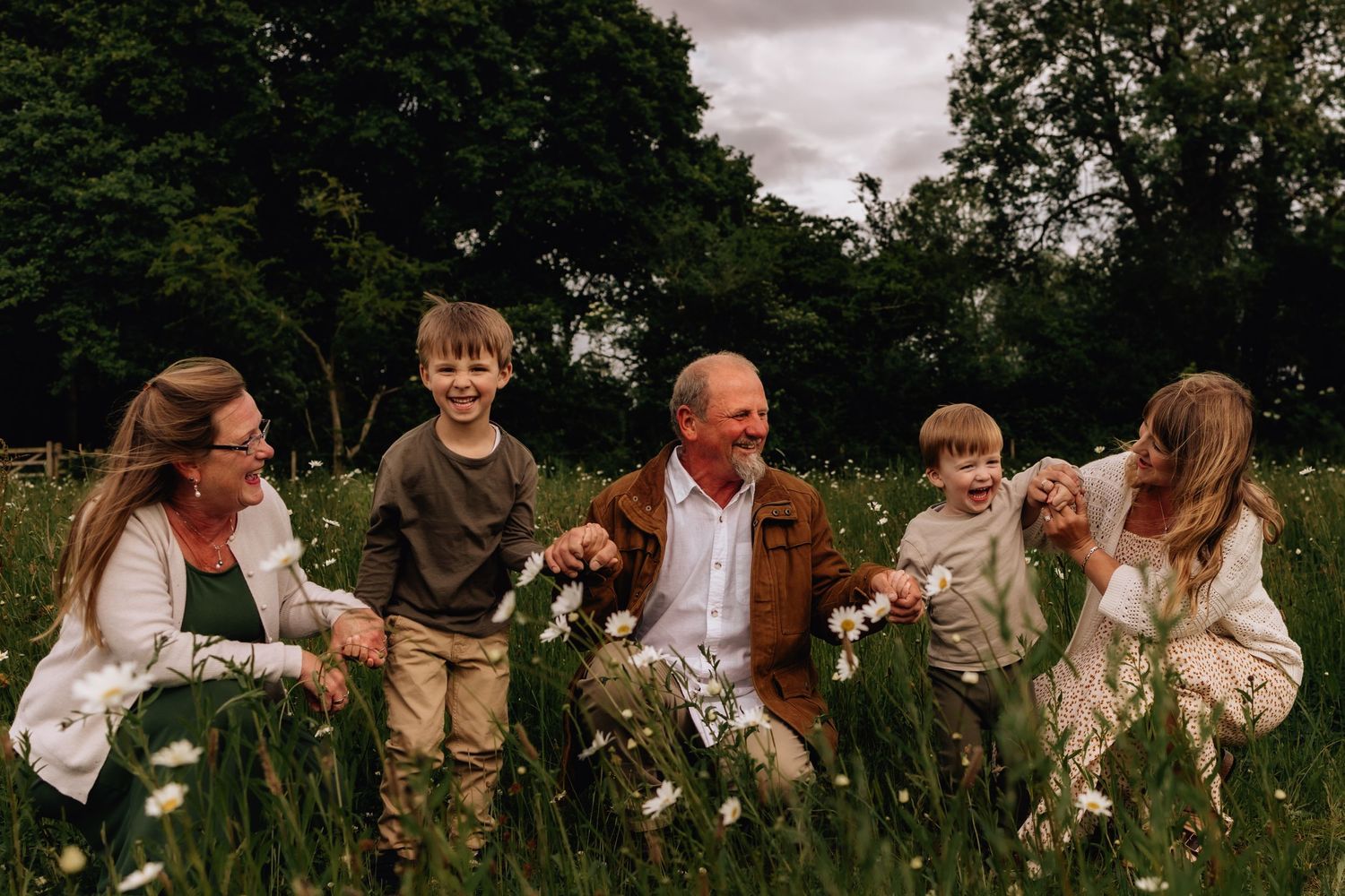 Family spending time together outdoors sitting in a wildflower meadow on a cloudy day.
