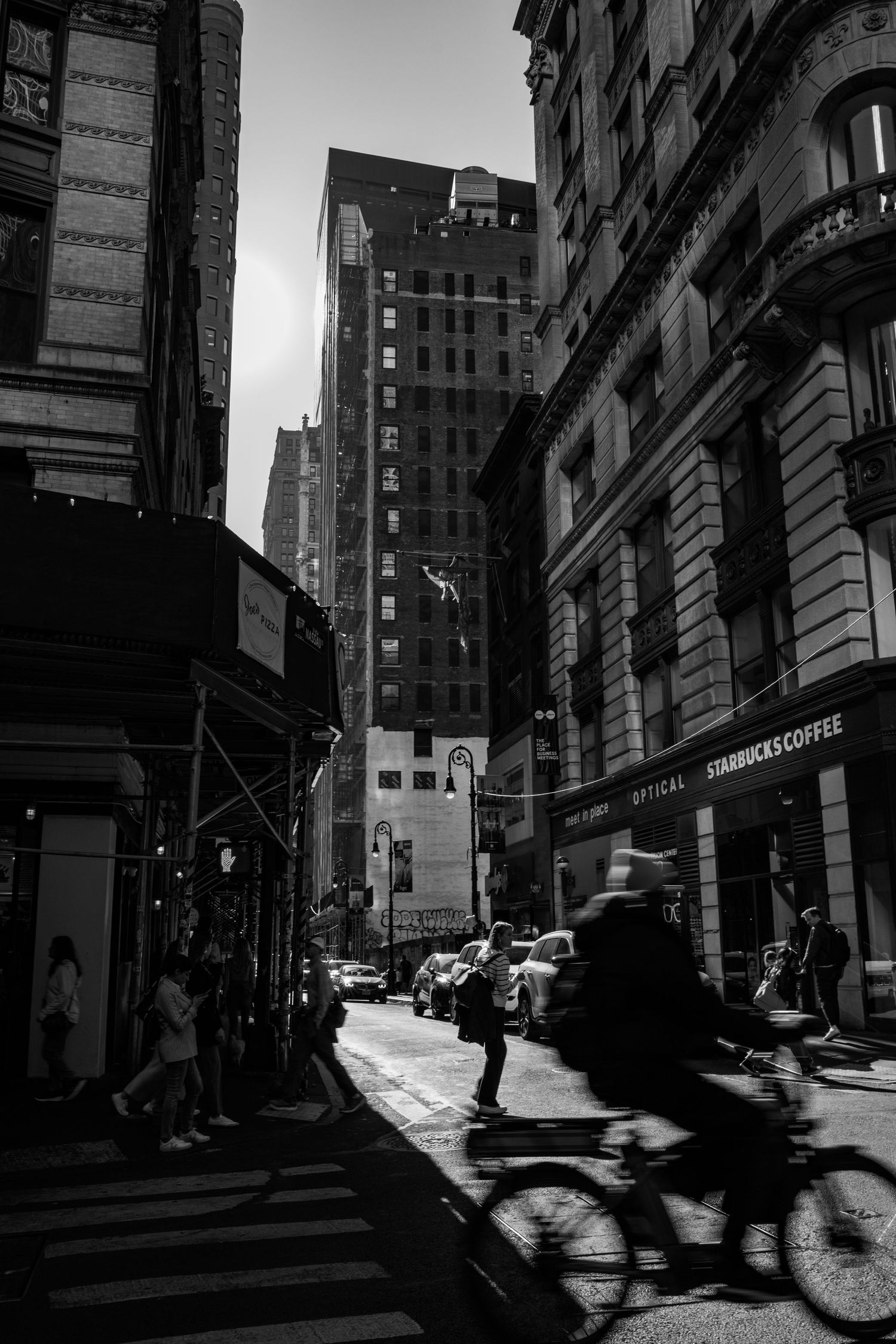Black and white urban street scene with cyclist and tall buildings in New York City.
