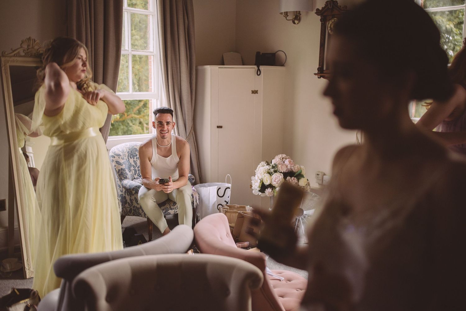 People gathered in a sunlit room with yellow dress and furniture preparing for a special occasion.