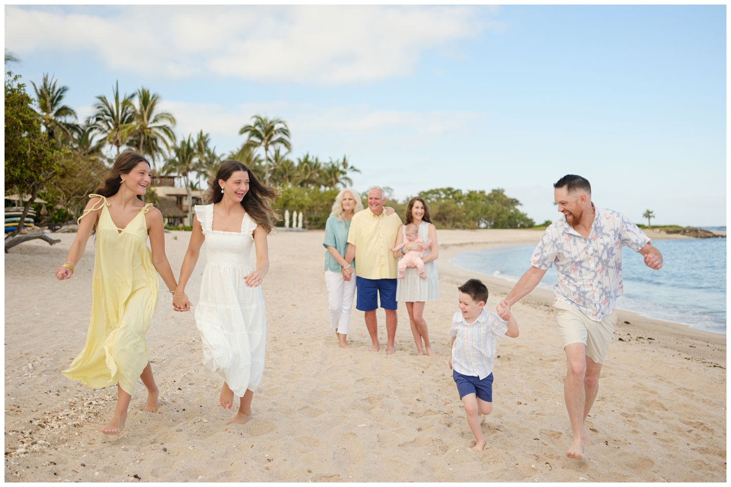 Family group enjoying a sunny walk together on a tropical beach with palm trees and gentle waves in Hawaii.