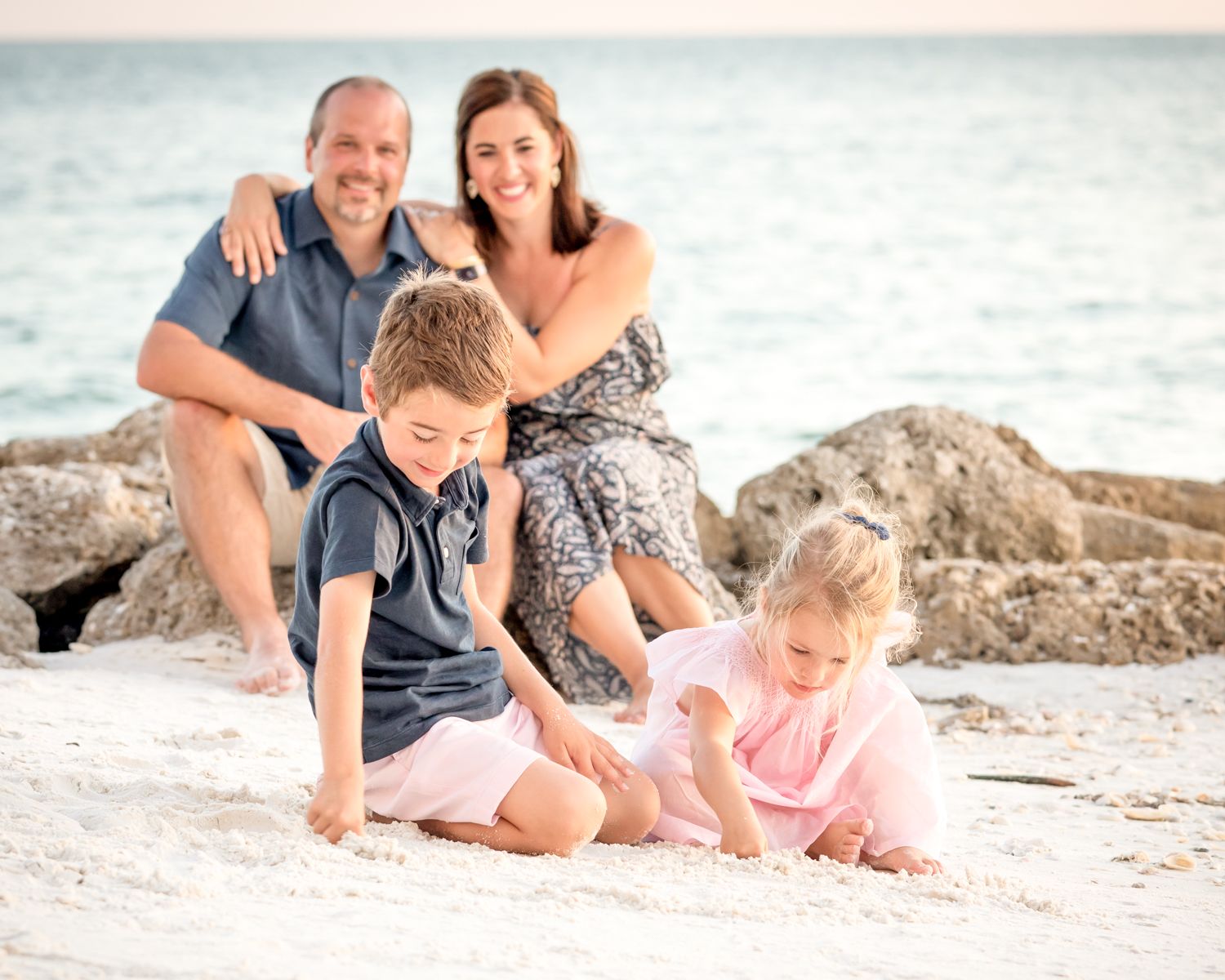 Happy family sitting together on a sandy Marco Island beach during sunset creating a series of casual candid beach portraits.