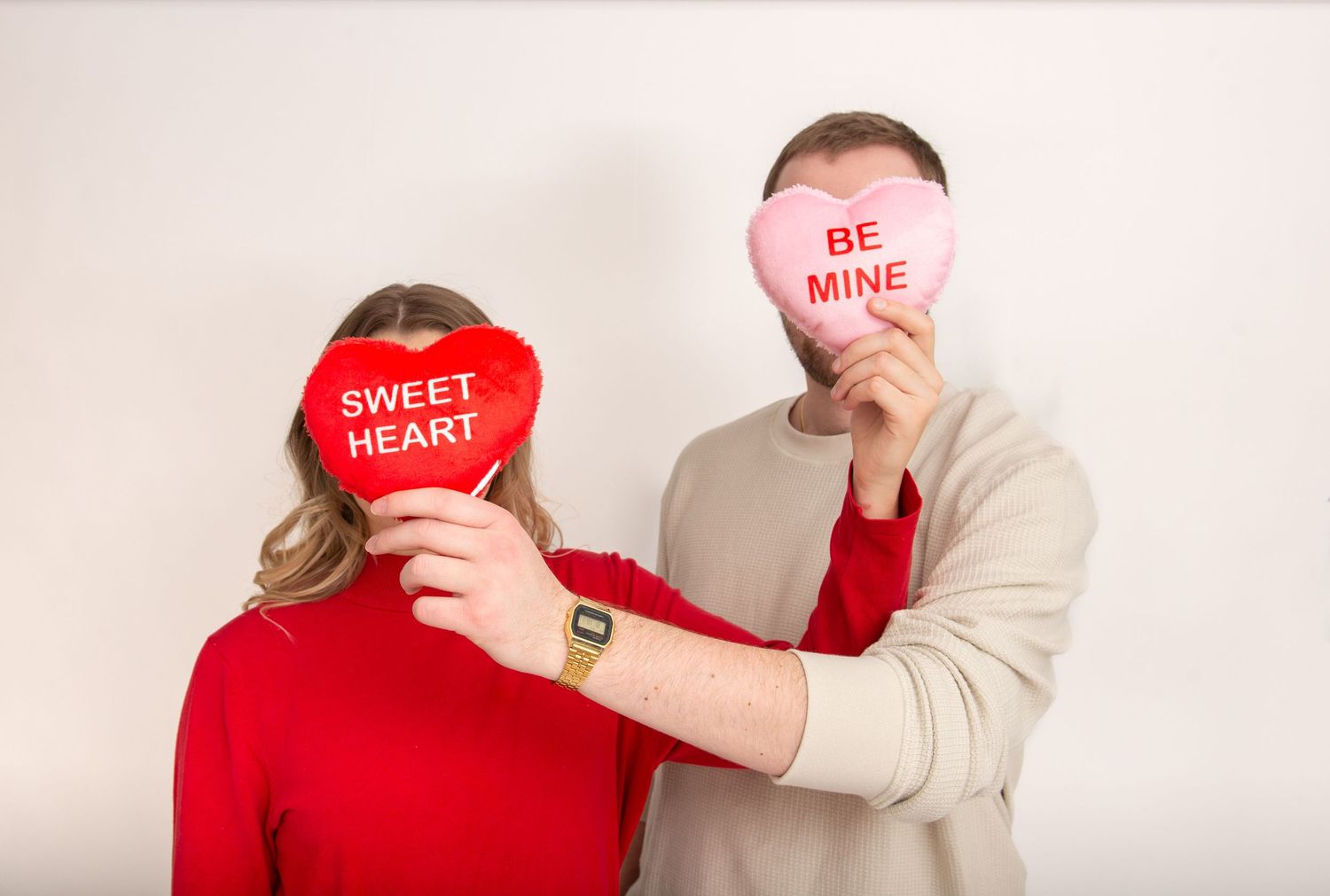 Couple holding Valentine-themed heart signs in a romantic photo.