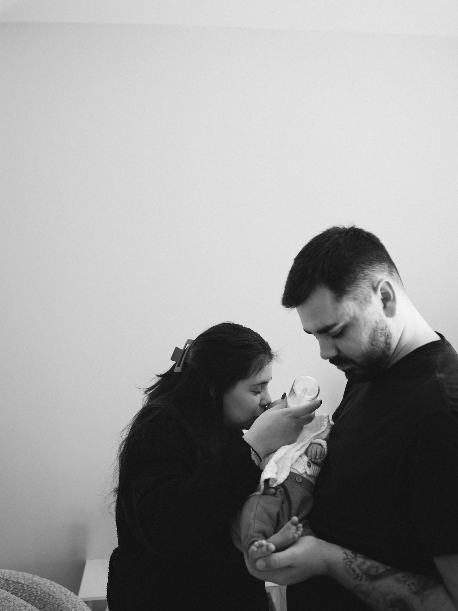 Newborn photo session at home. Family cuddling and feeding in fact while admiring the baby. Centerville, Ohio.