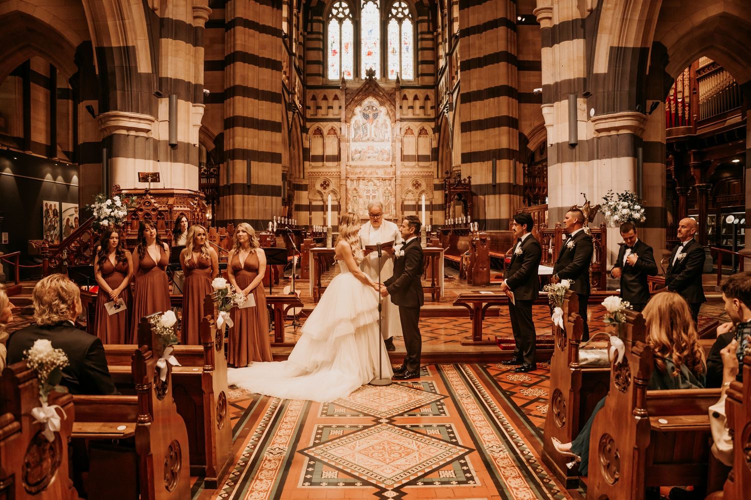 A traditional church wedding ceremony is held in a beautiful cathedral with ornate architecture and stained glass windows.