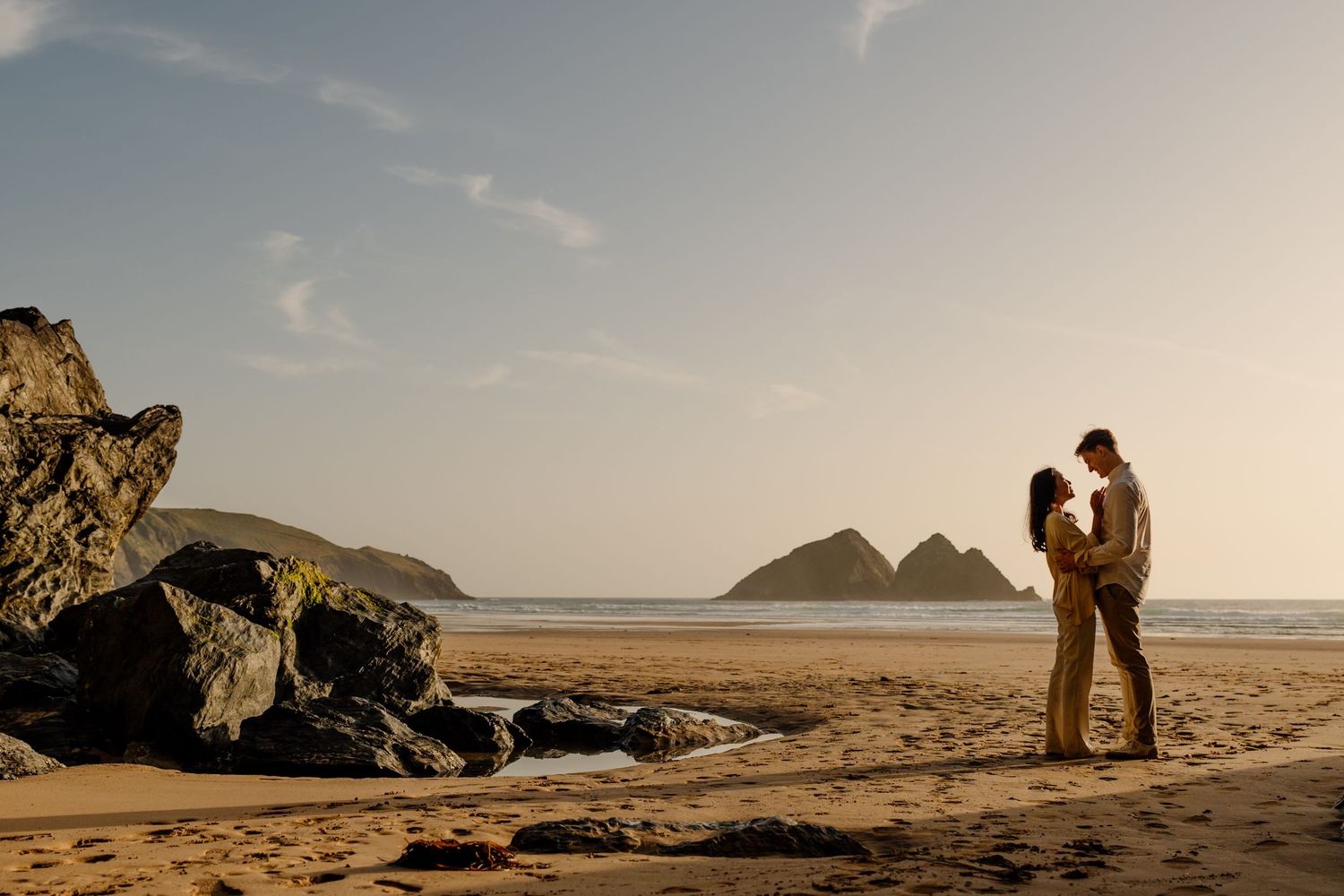 Couple sharing a romantic moment at holywell bay in cornwall after a surprise proposal