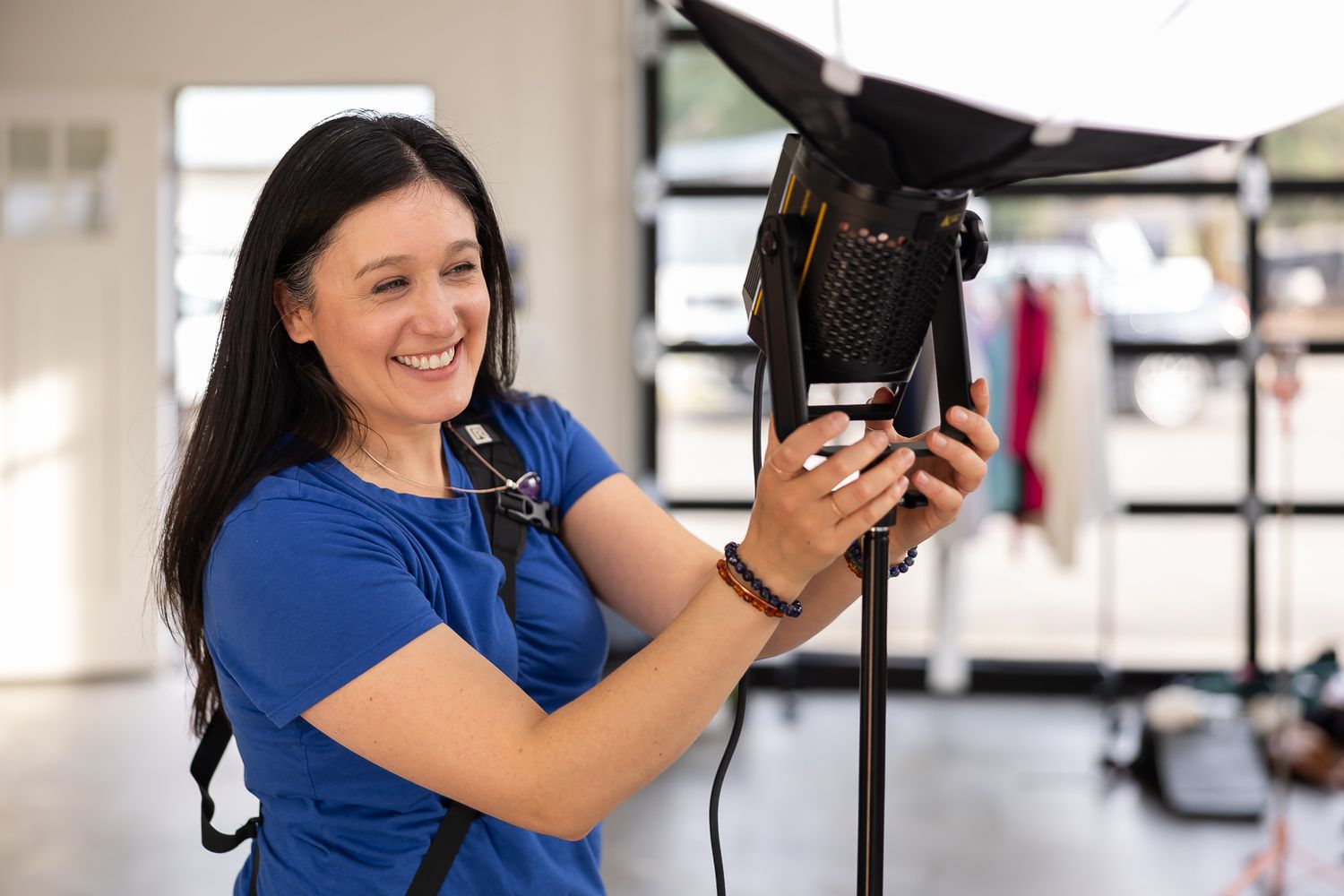 woman branding photographer hands on consistent light setup for photoshoot in Bellevue, WA smiling at client off screen wearing blue shirt