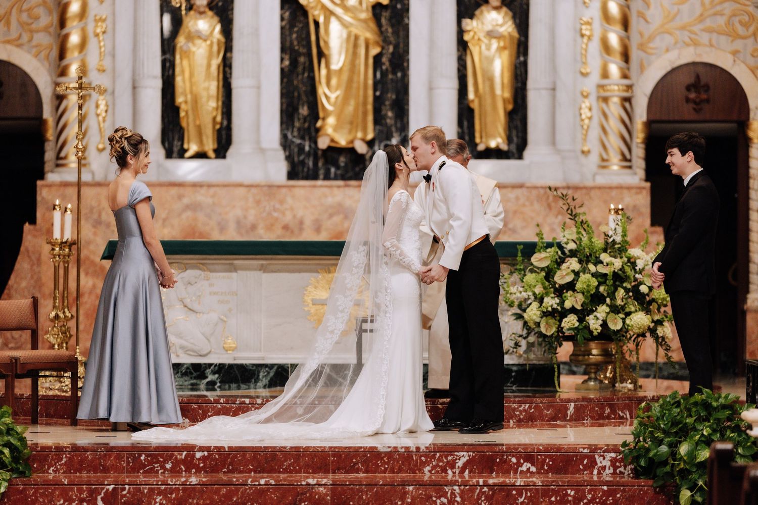 Elegant wedding ceremony in ornate church with gold accents and floral decorations creating a romantic atmosphere.