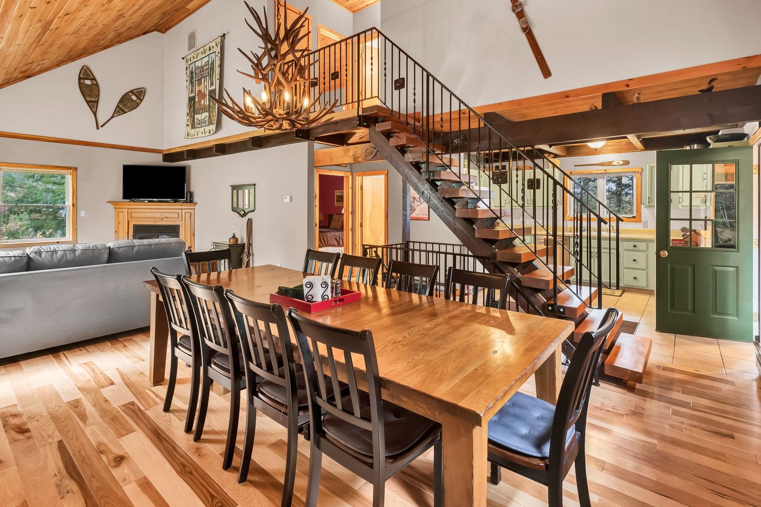 Panoramic view of a rustic open concept living space with wood beams, hardwood floors and modern furnishings.