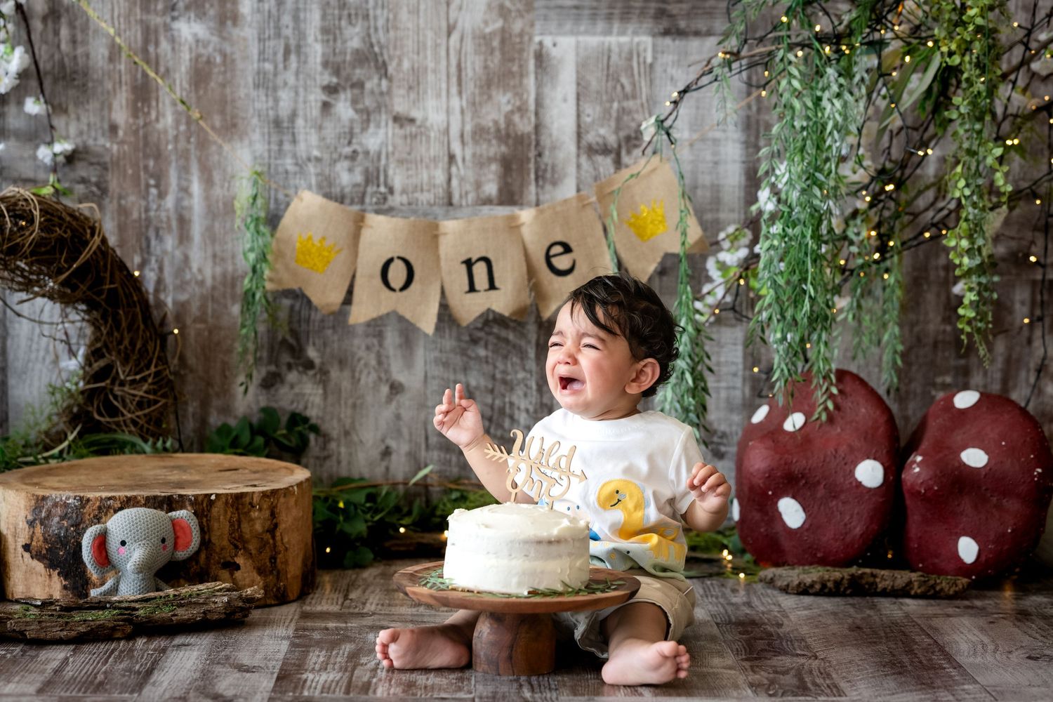A festive first birthday setup with pink and purple balloons, silver 'ONE' letters, and a smash cake celebration.