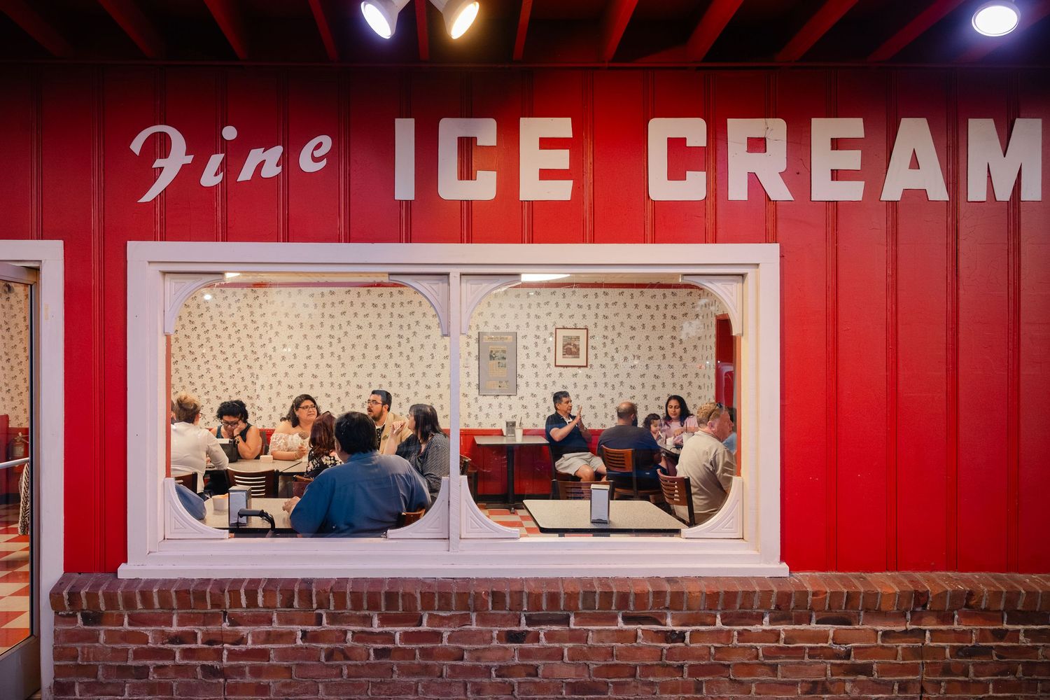 A vintage red ice cream parlor interior with retro seating booths and classic signage on the wall.