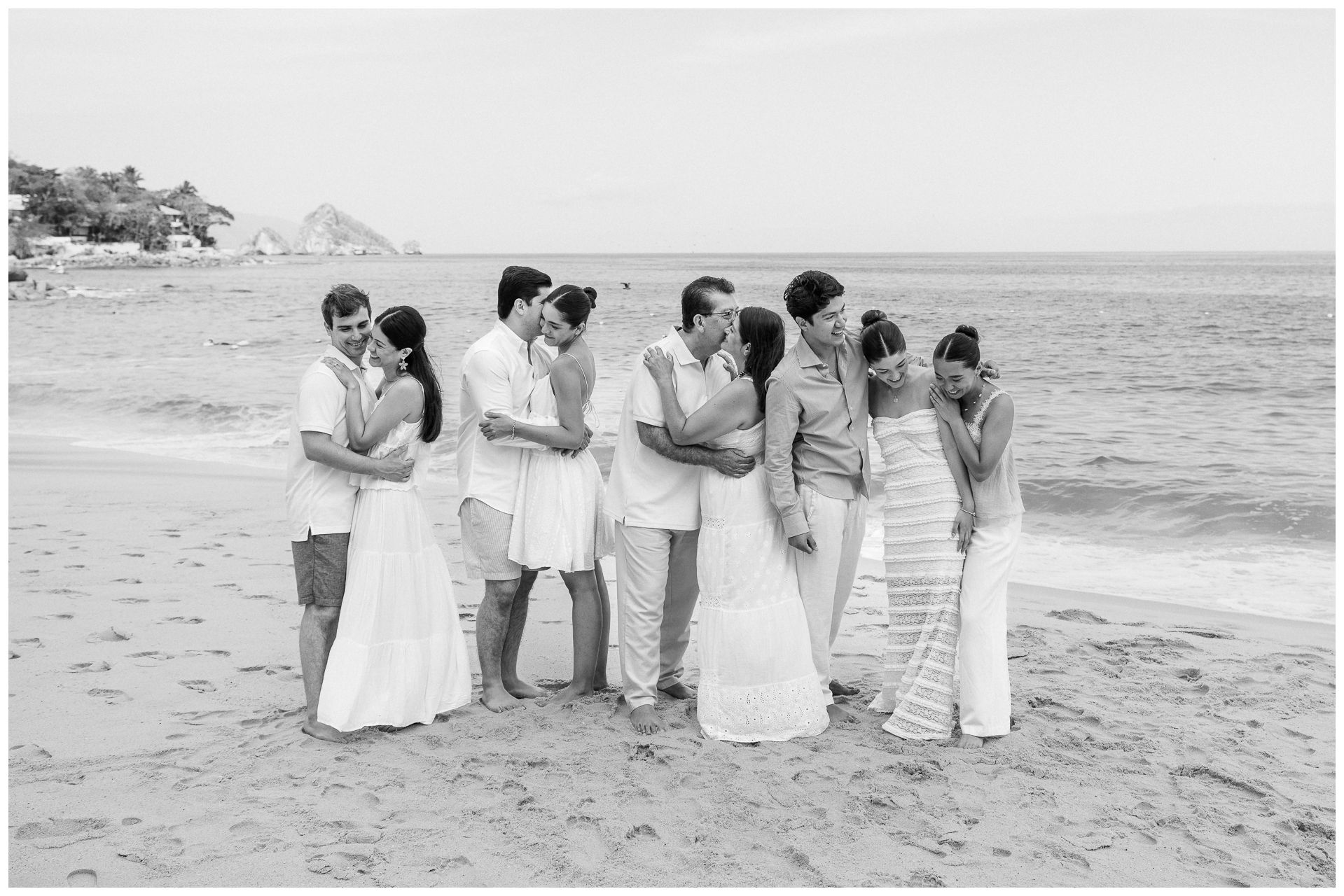 Puerto Vallarta Family Photographer captures Beach Family Photos of parents embracing on a sandy beach by the ocean.