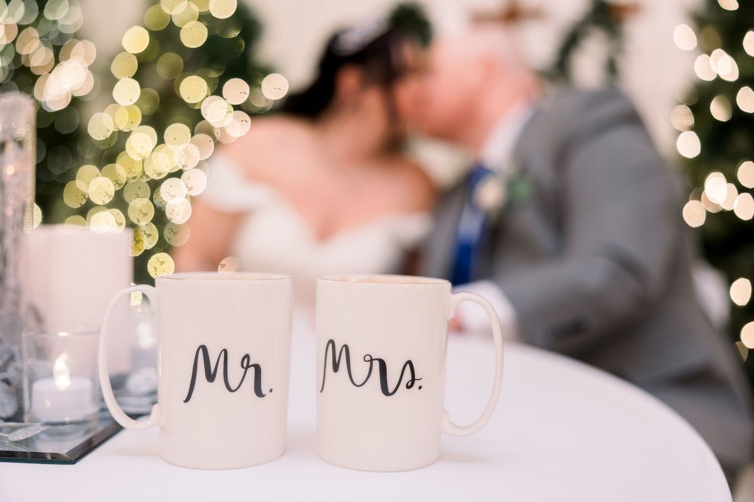 Winter wedding reception table decorated with glowing candles, flowers and Mr & Mrs signage in an elegant evening setting.