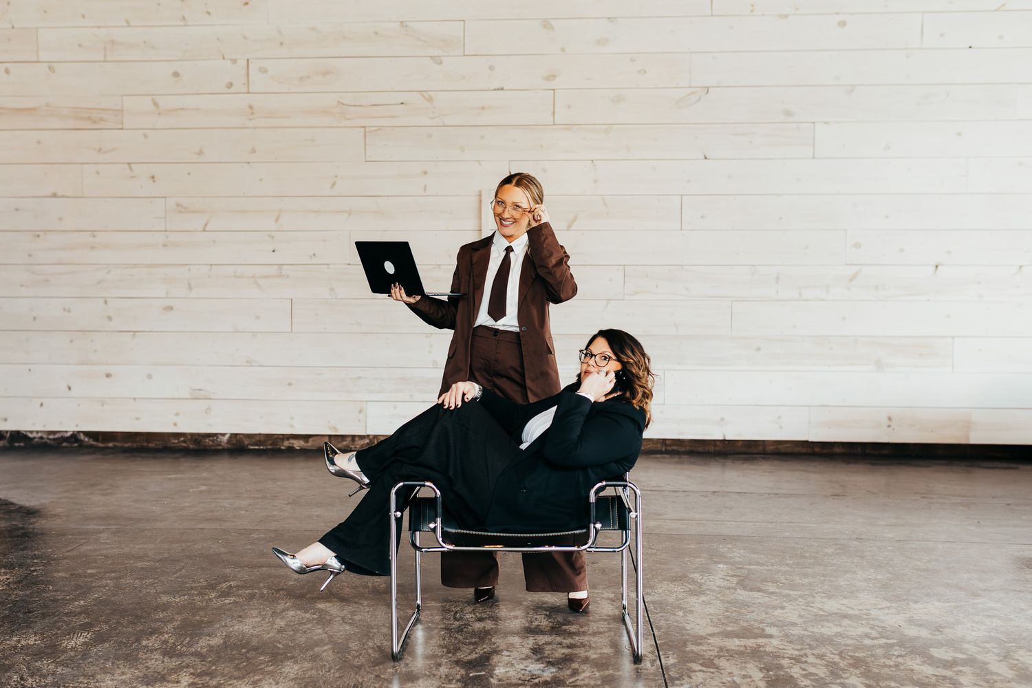 Professional sitting in office chair against white brick wall in empty industrial space.