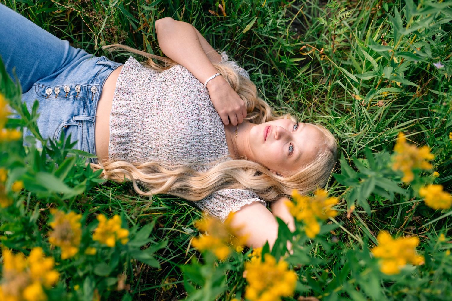 Senior girl lying in a meadow of yellow wildflowers in American Fork Canyon