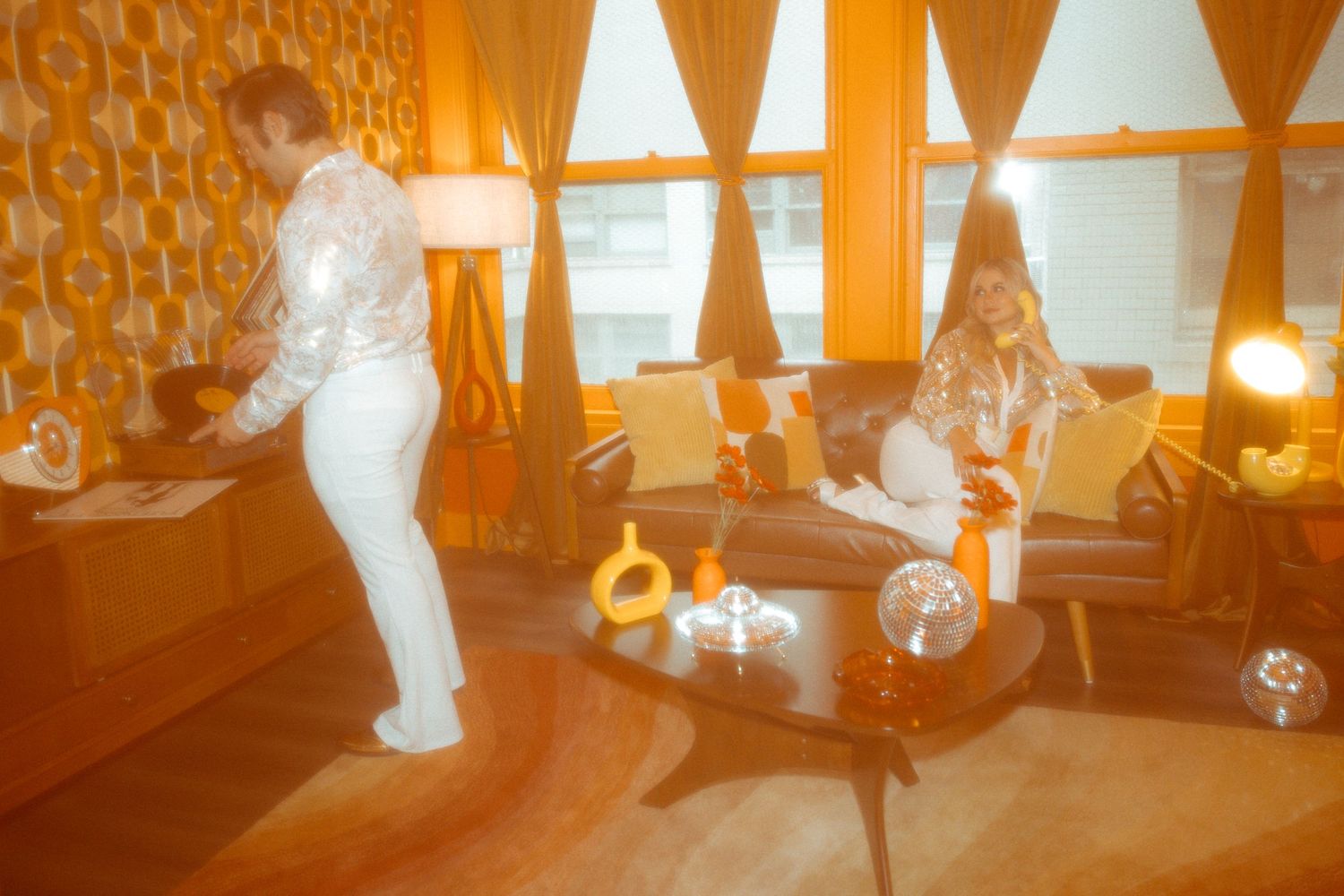 A retro-styled room with orange lighting and people in casual attire.