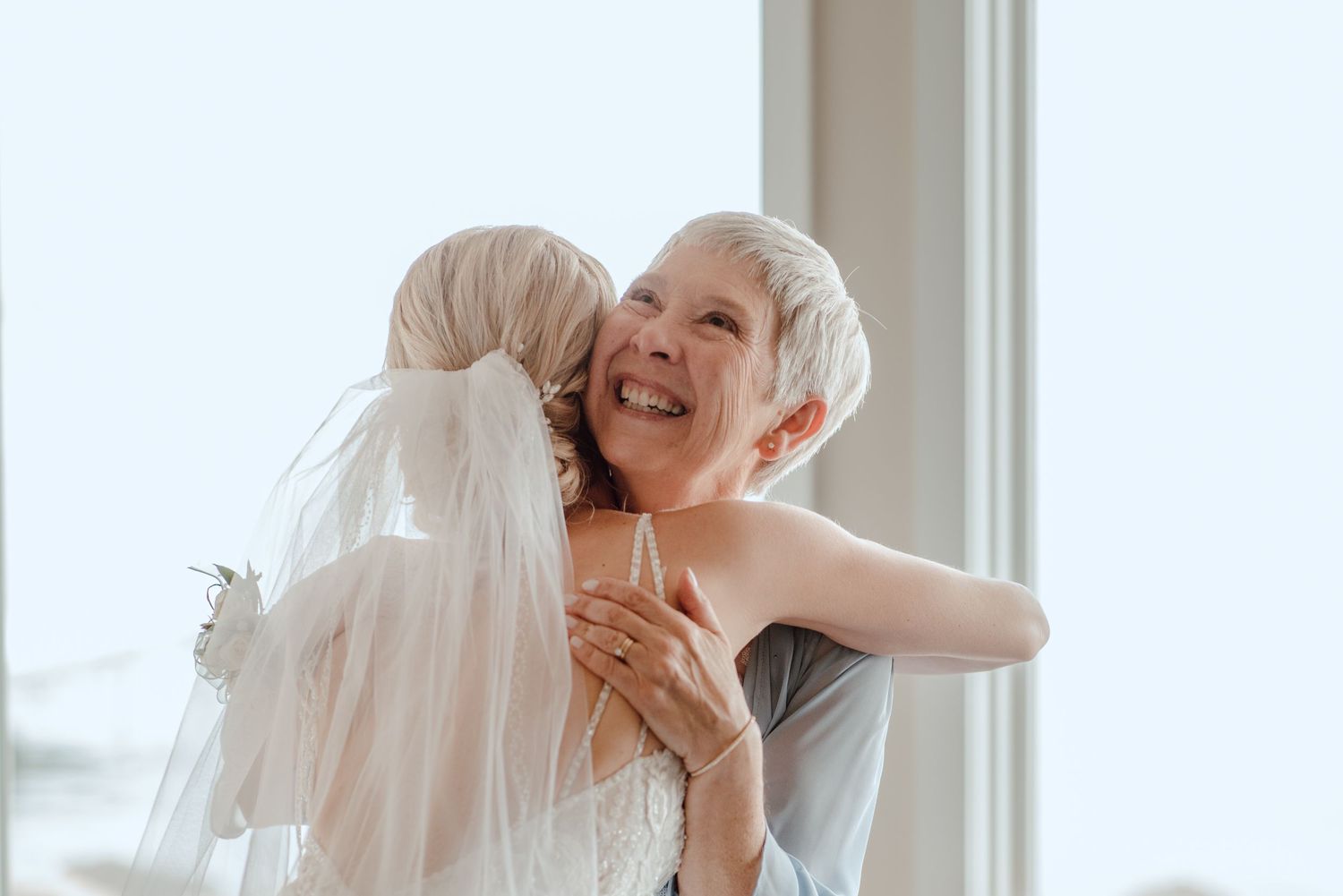An emotional moment shared between two people during a wedding, with soft window light.