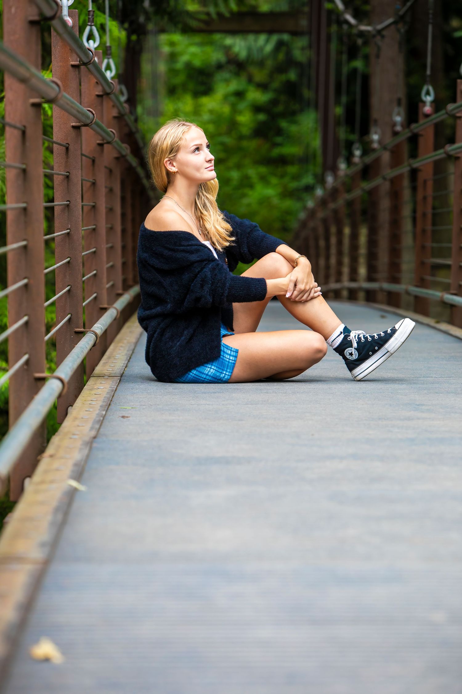 A person lying on a wooden bridge walkway in a relaxed pose wearing shorts and sneakers.