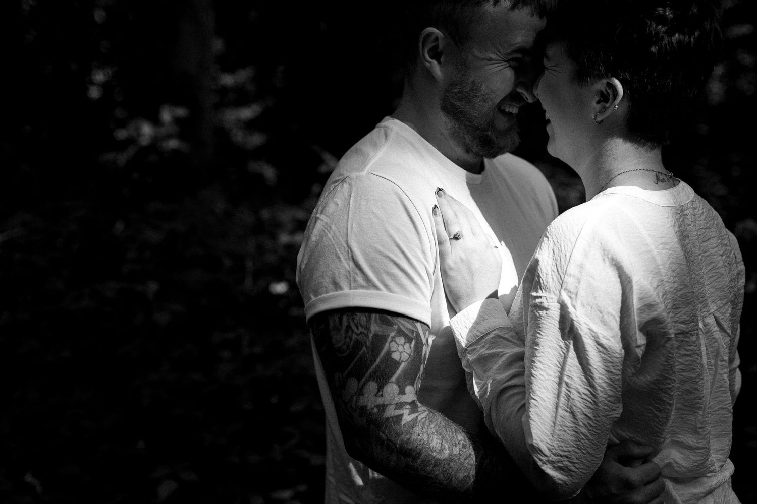 A romantic black and white portrait of a couple sharing an intimate moment in nature.