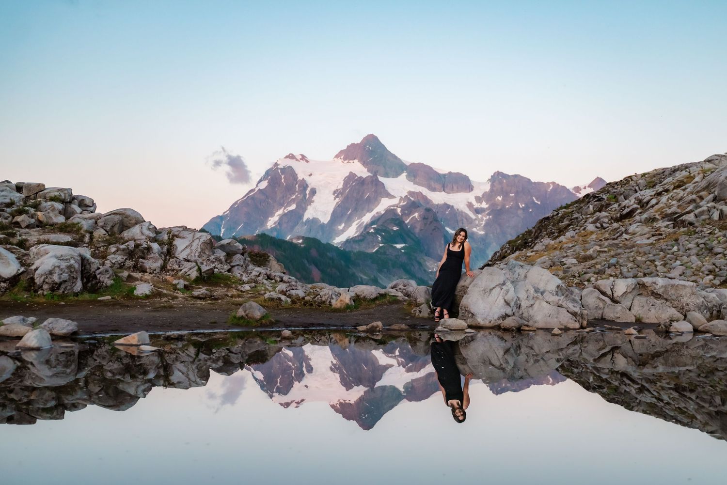 senior girl poses in front of reflective water at artist's point backed by mt shuksan