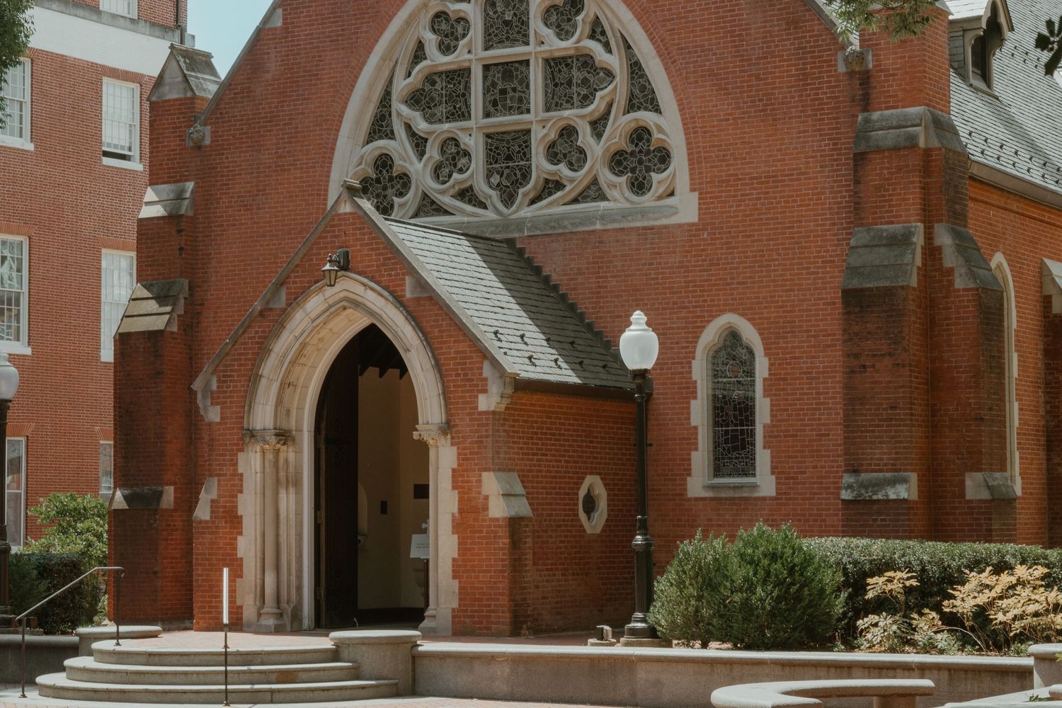 Red brick church entrance with gothic arched doorway and ornate window details.