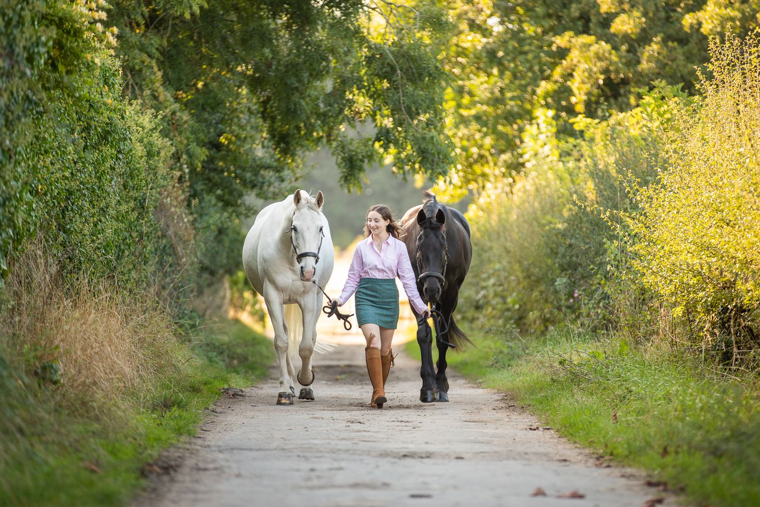 Walking down a country path with two horses on a sunny afternoon.