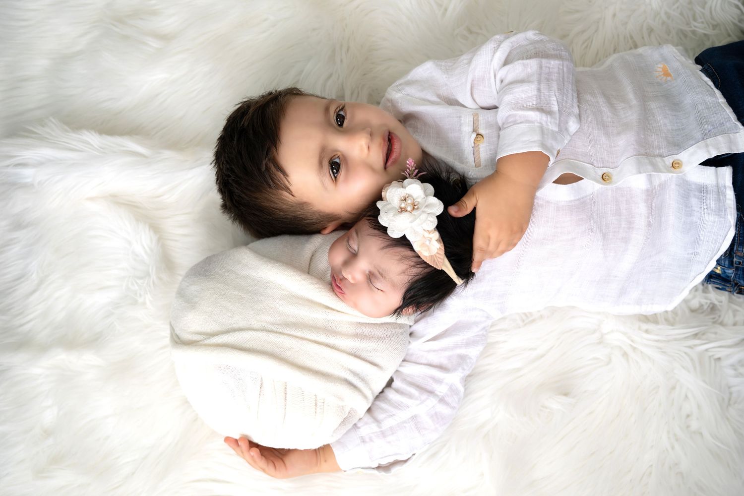 Sibling holding newborn in a cozy studio session with a new born photographer Dubai, capturing a tender family moment