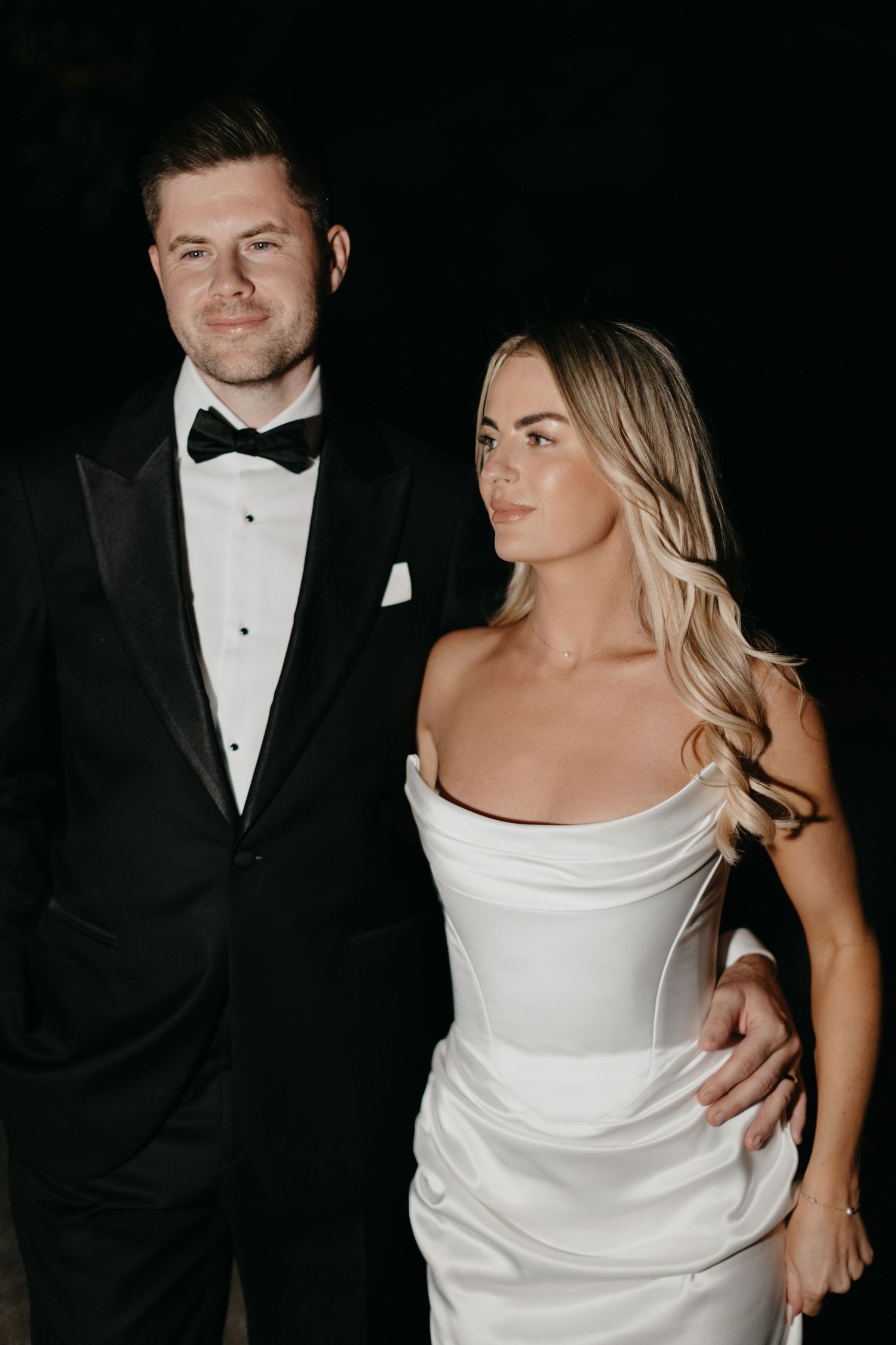 A series of romantic wedding photos showing a couple walking and posing along a garden pathway lined with green shrubbery.