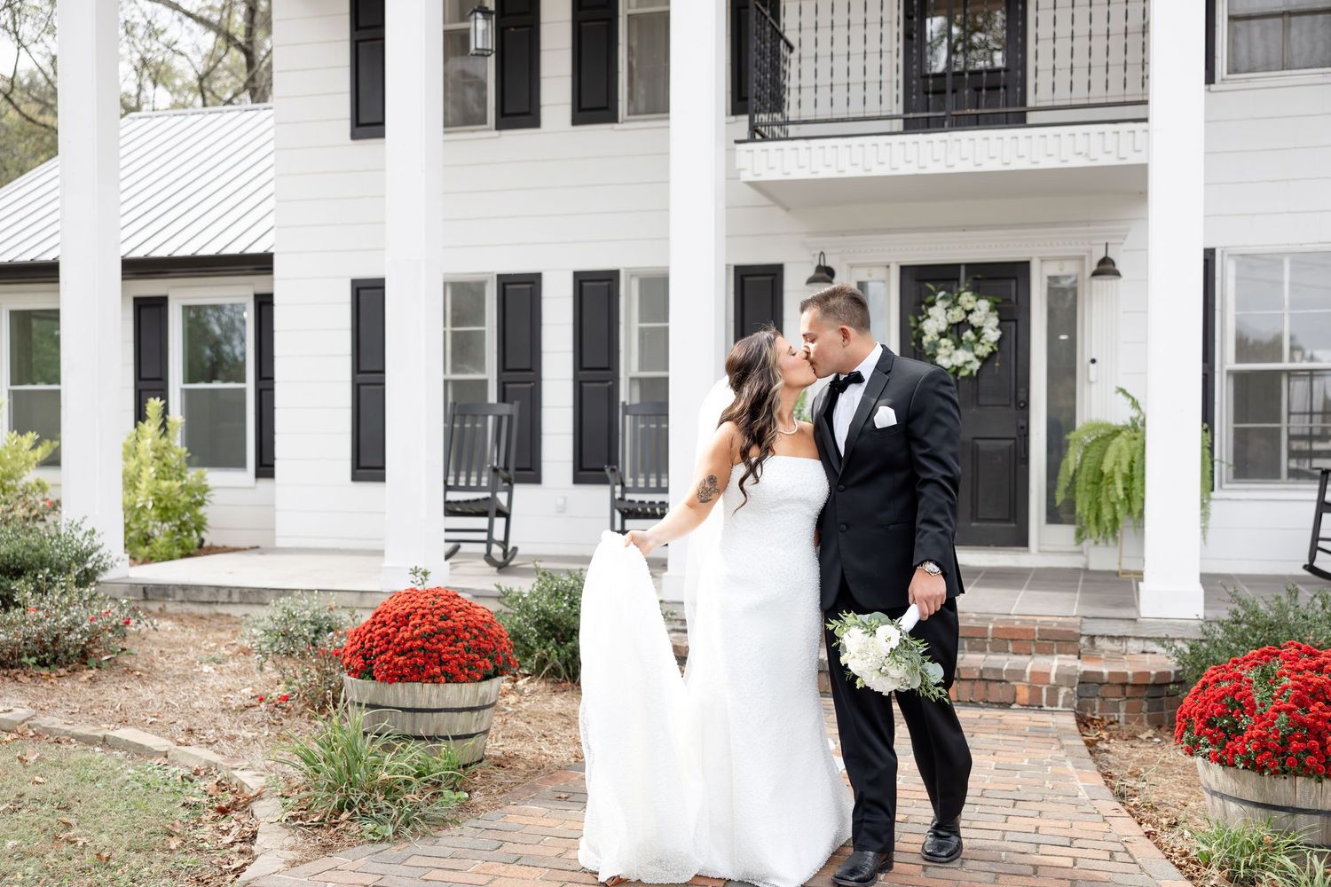 Bride and groom kiss in front of The Upton House wedding venue in Guntersville, Alabama. Elegant wedding at The Upton House in Guntersville