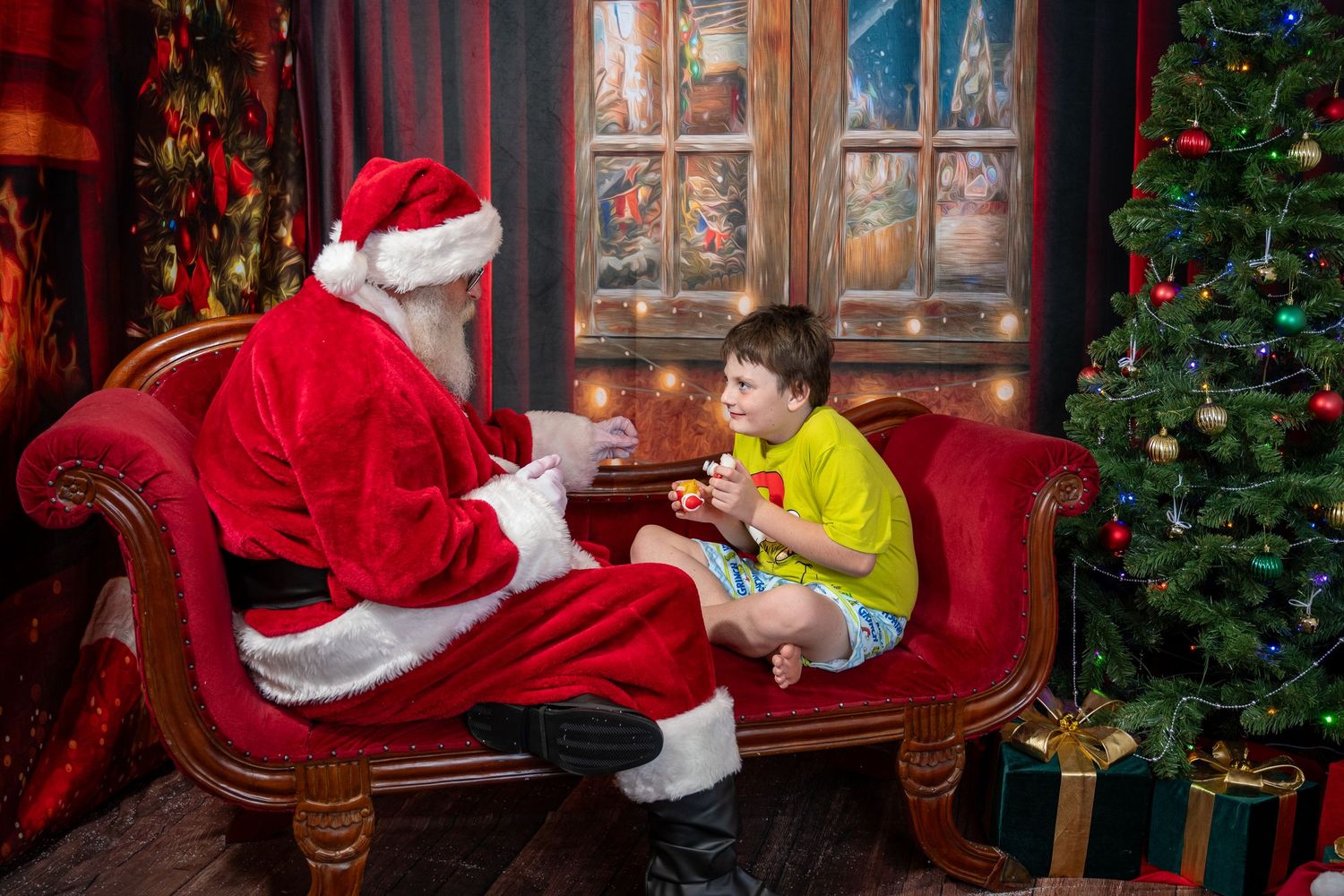 Holiday scene with Santa Claus on red velvet chair near decorated Christmas tree.