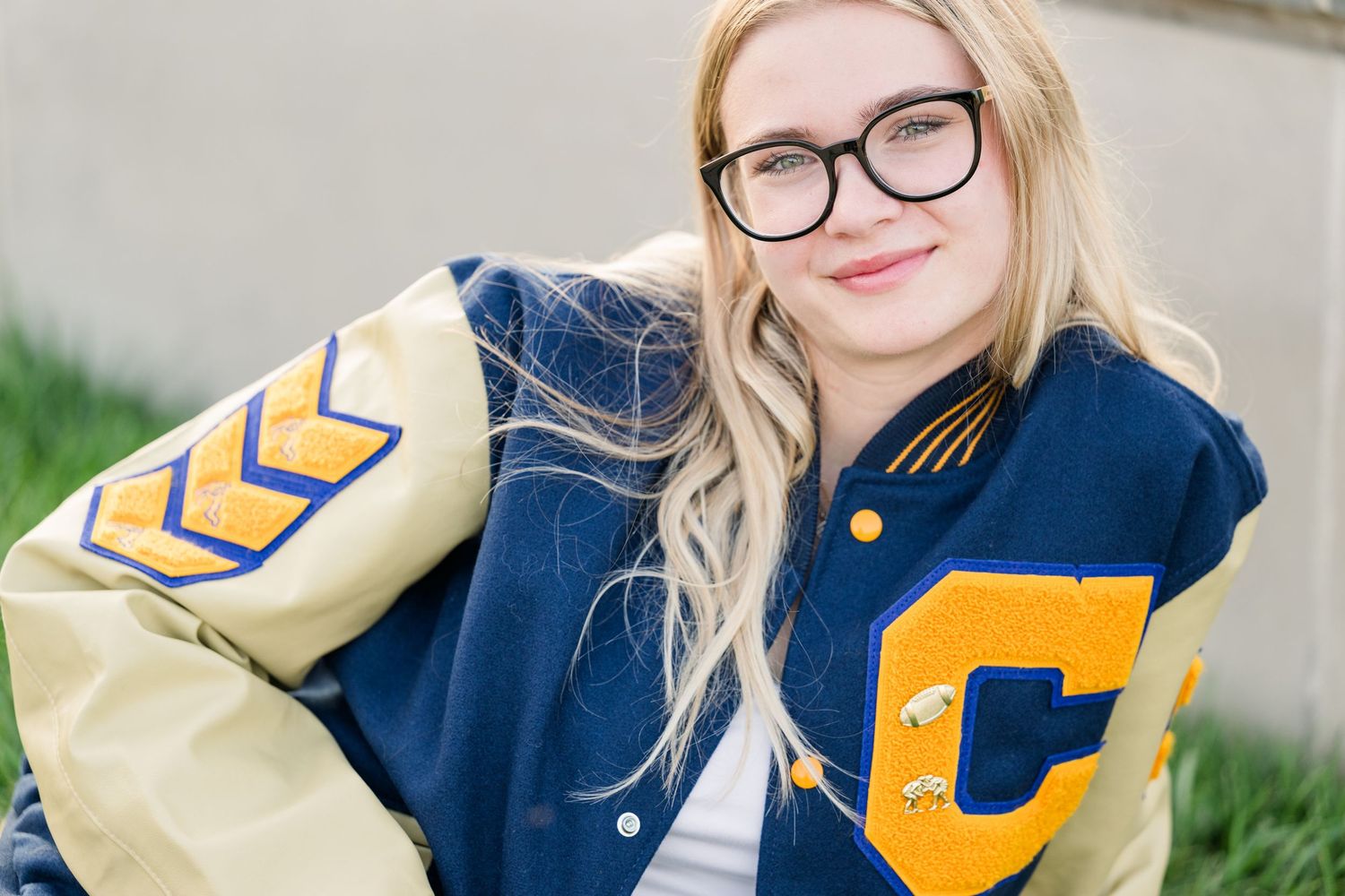 Senior portrait of graduating female high school girl in varsity jacket at Coxhall Gardens in Carmel Indiana near Indianapolis