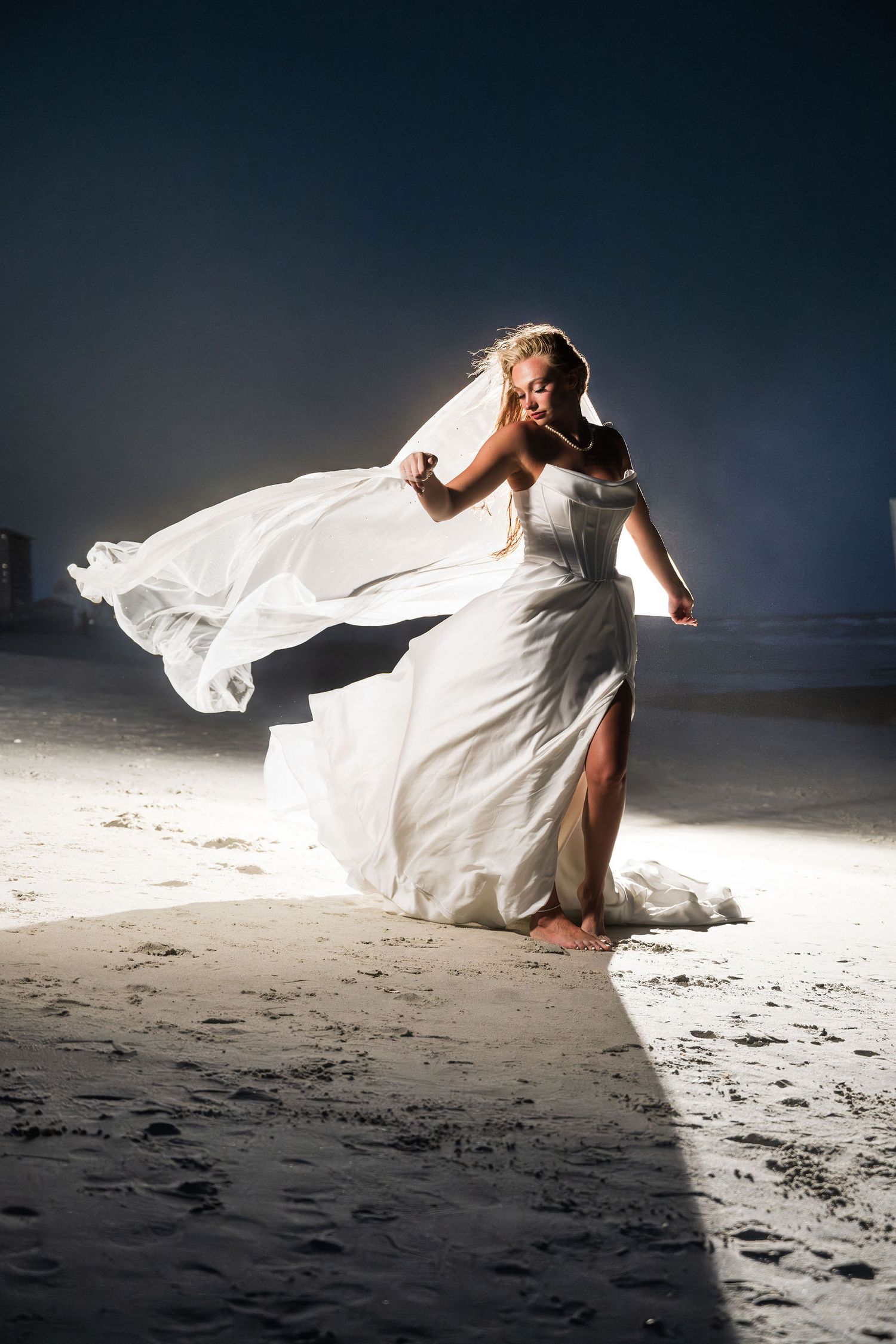 A silhouetted side profile of a bride in a white wedding dress with veil against a bright background.