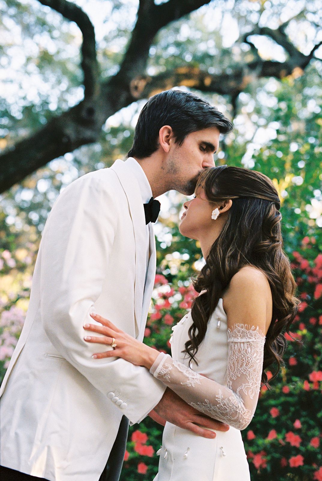 A wedding ceremony in a wooded setting with white draped fabric decor and a Persian rug aisle runner.