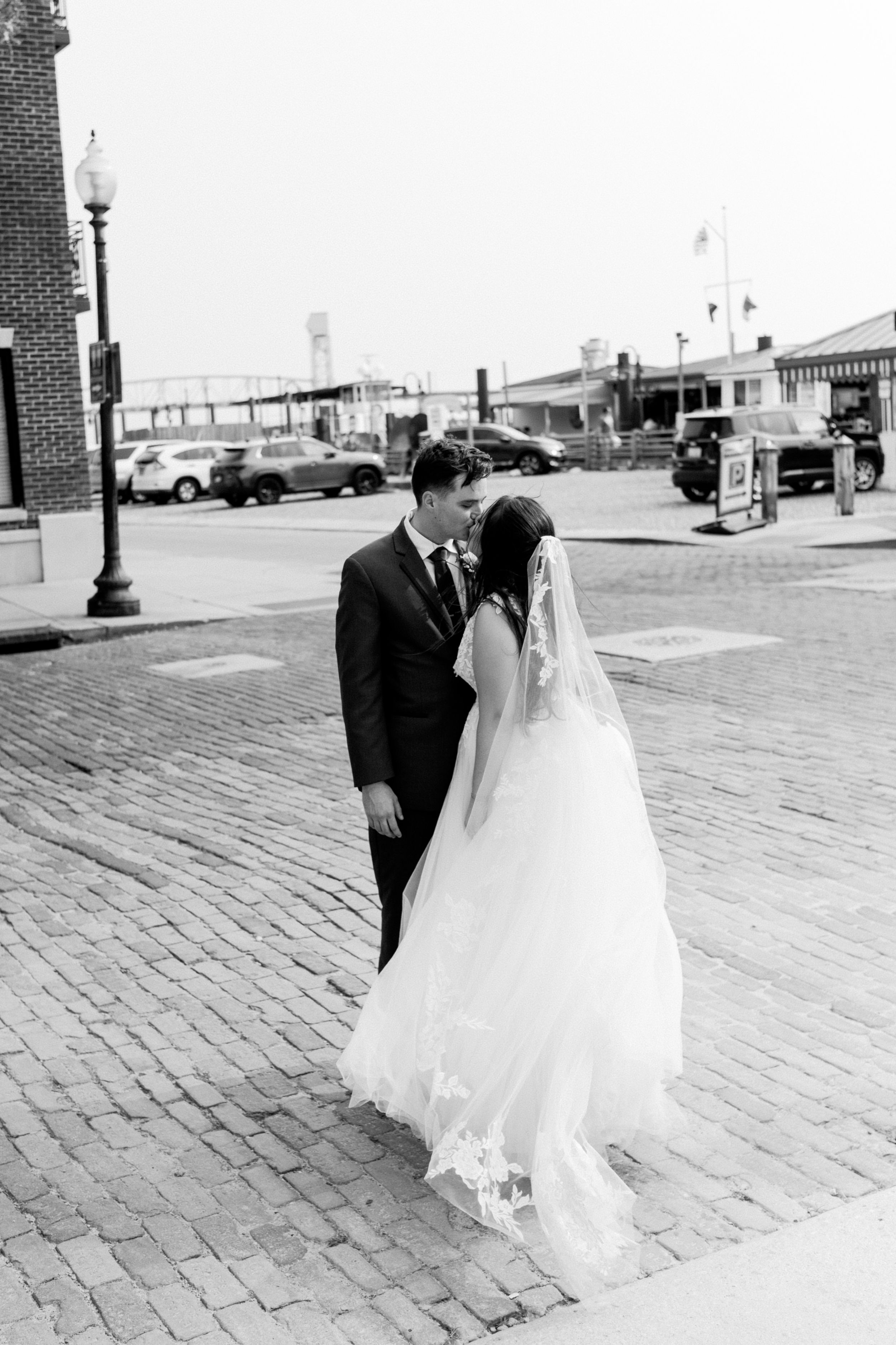 A couple in wedding attire walks across a brick paved area in a series of romantic black and white photos.