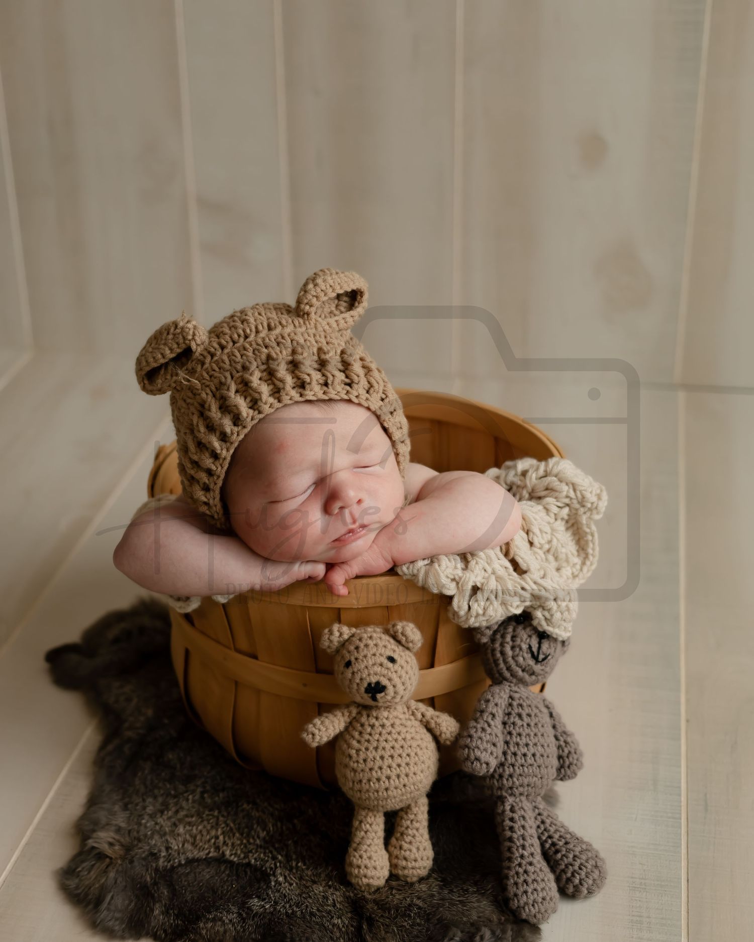 Newborn baby sleeping in wooden basket with knit bear hat and toy companions.