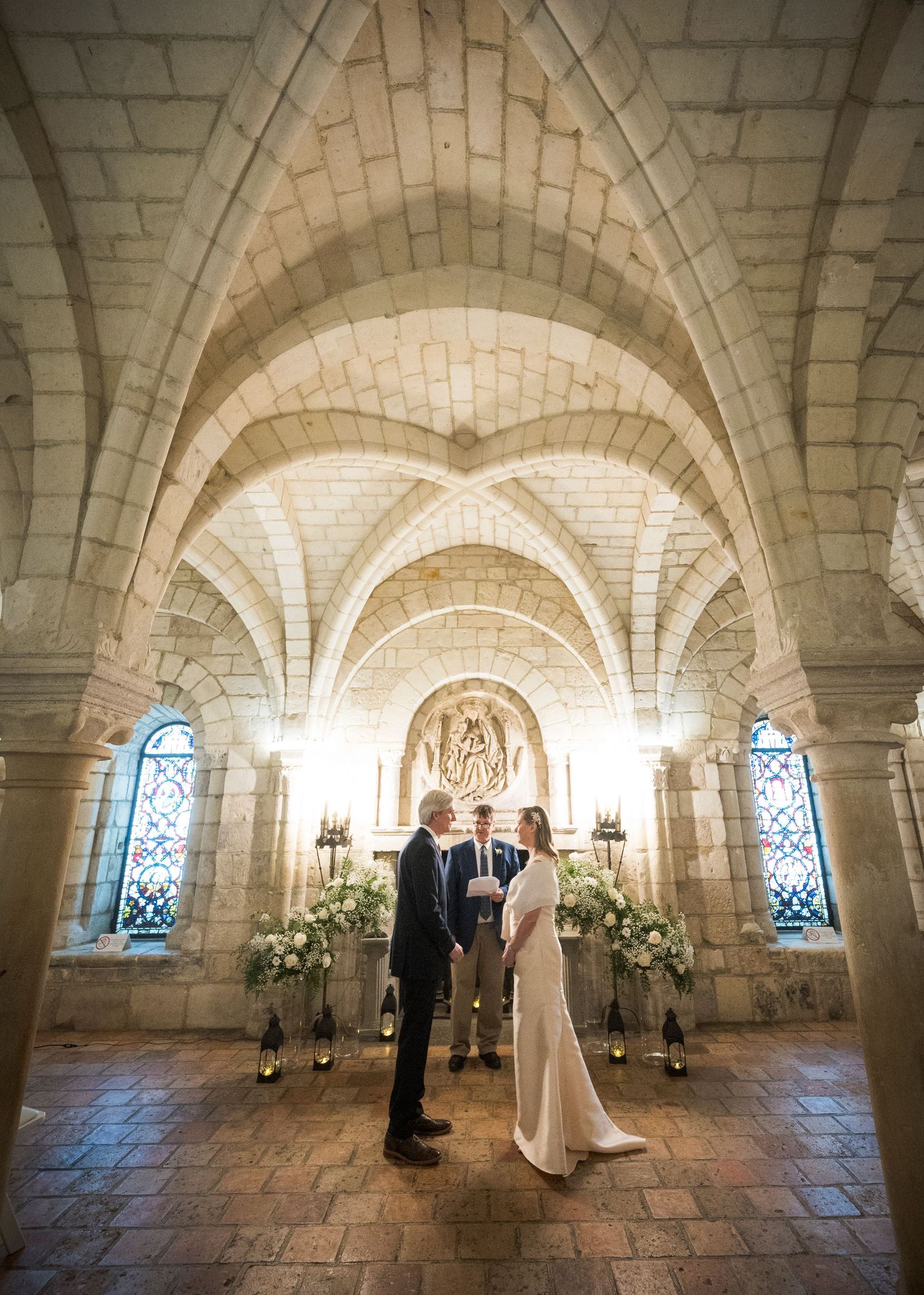 A wedding ceremony in a beautiful stone chapel with vaulted ceilings and stained glass windows.