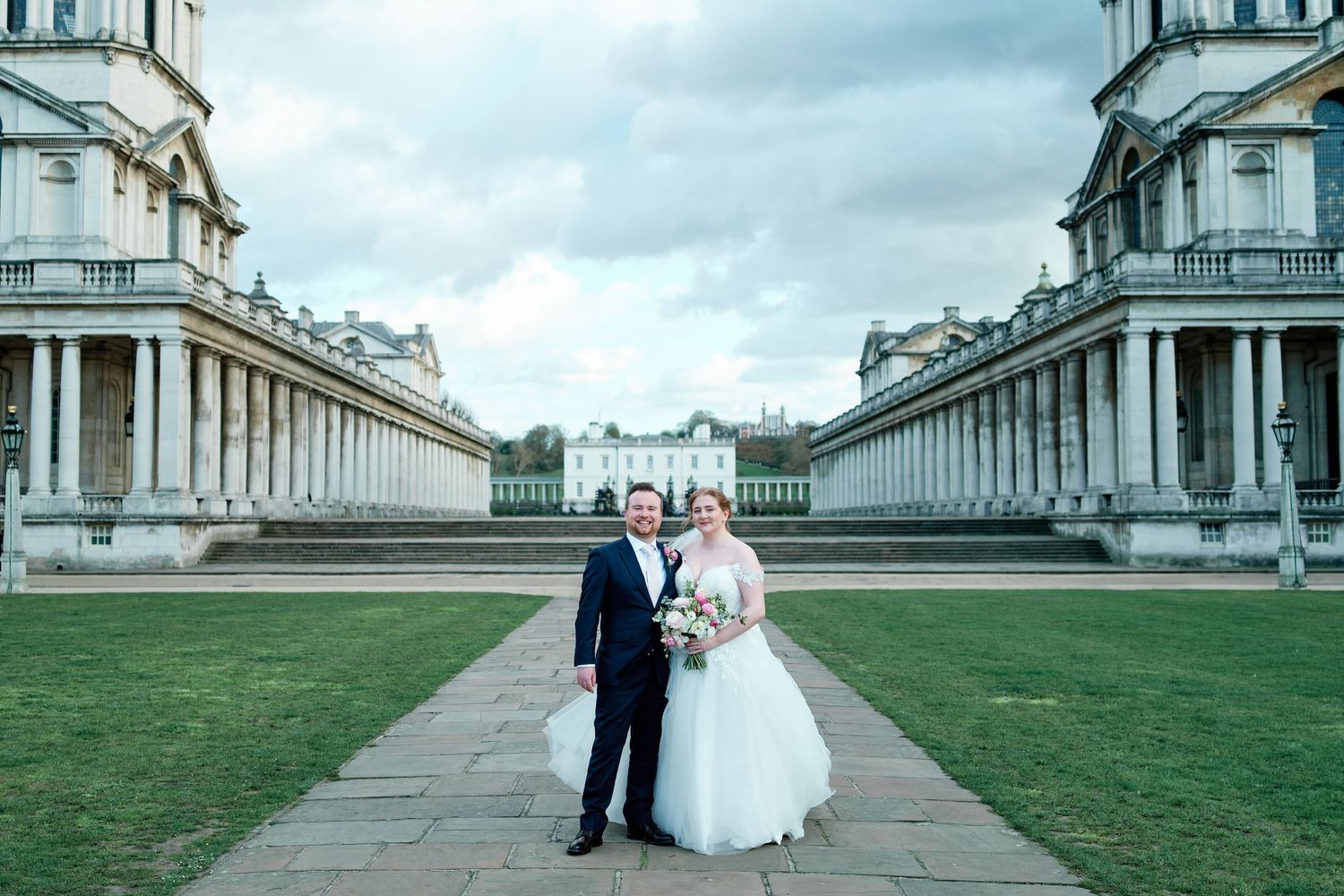 Bride and groom pose together at the Old Royal Naval College in Greenwich, London, on their wedding day.