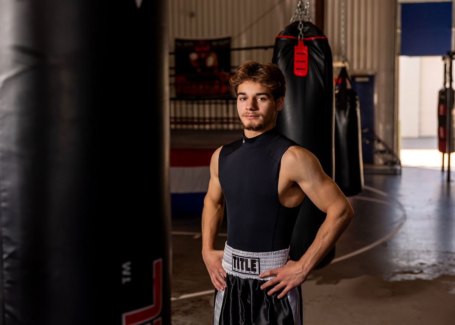 Athletic person in black workout attire stands confidently in a dimly lit hallway space.
