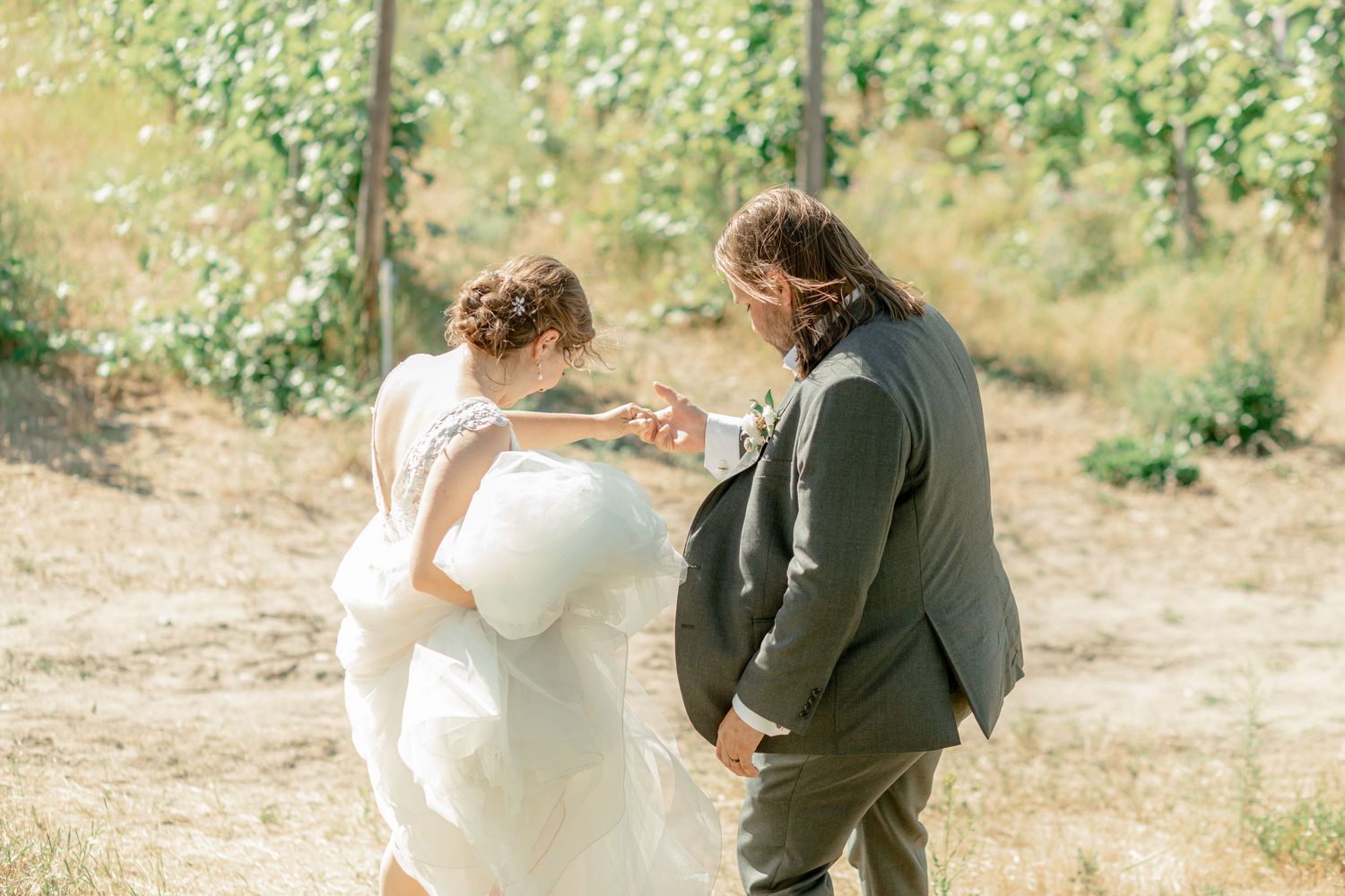 Bride and groom share a tender moment exchanging rings outdoors in a sunlit vineyard setting in Hampshire UK