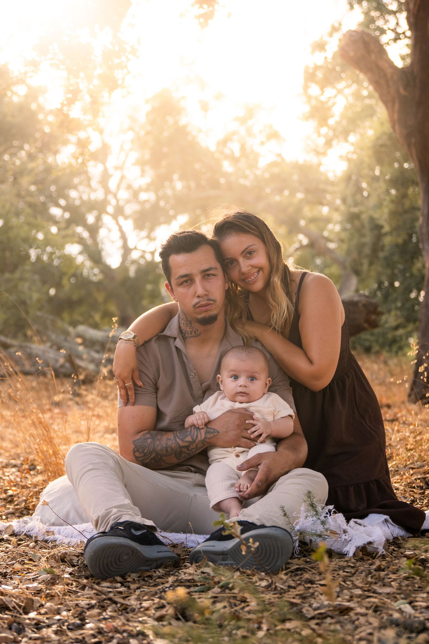 Family relaxing together on autumn leaves during golden hour sunset in the park.