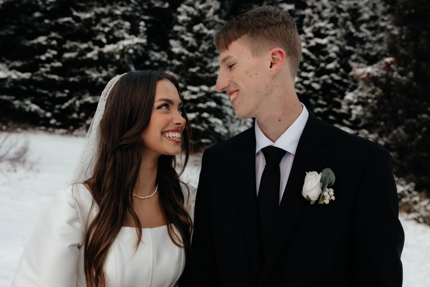 Black and white photo of a bride and groom sharing a romantic moment under a lace wedding veil.