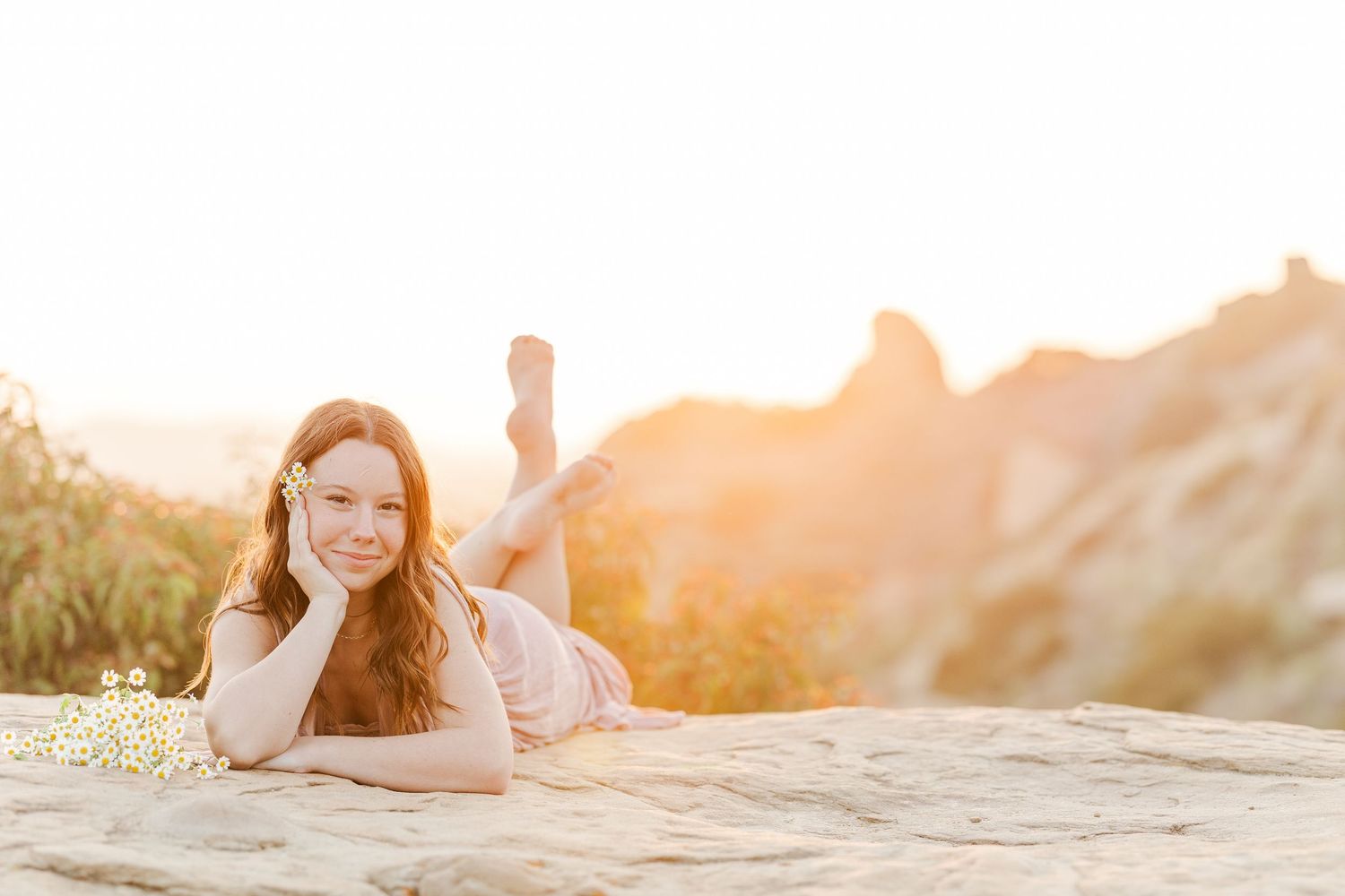 A person laying in soft grass during golden hour sunset with warm glowing light.
