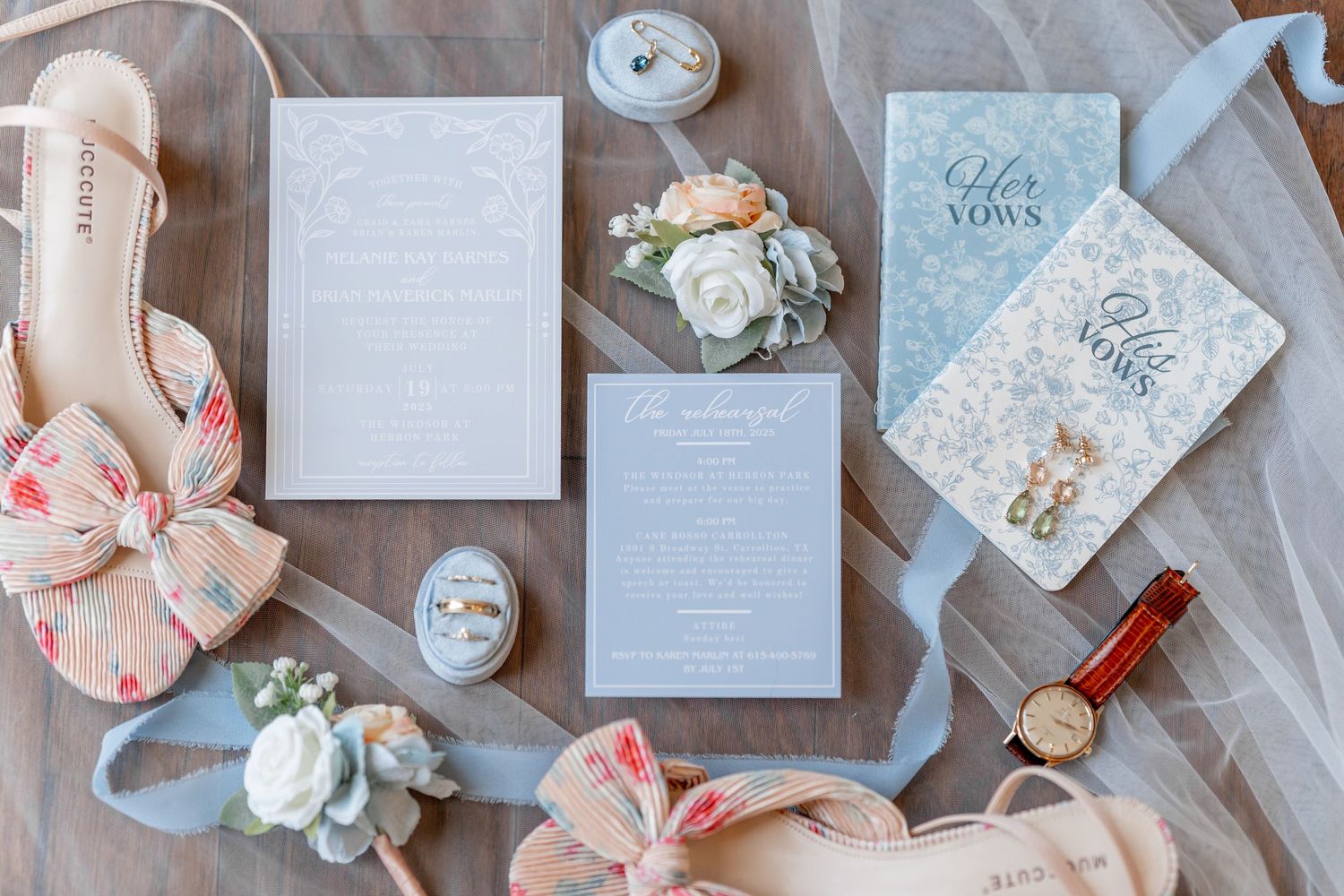 Elegant wedding invitation suite with pale blue and floral designs laid out with white roses and blush accents on gray fabric. DALLAS WEDDIN