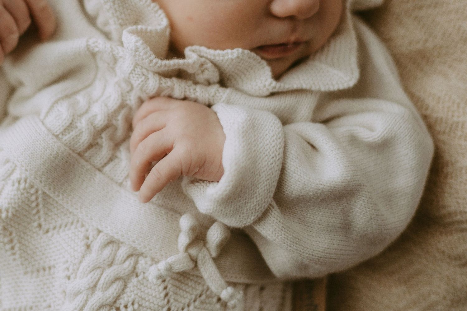 Close-up details of soft cream-colored knit fabric with delicate textures.