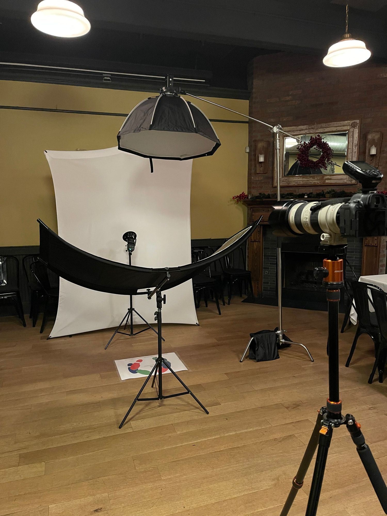 Professional studio lighting setup for corporate headshots with softbox, white backdrop, and curved reflector.