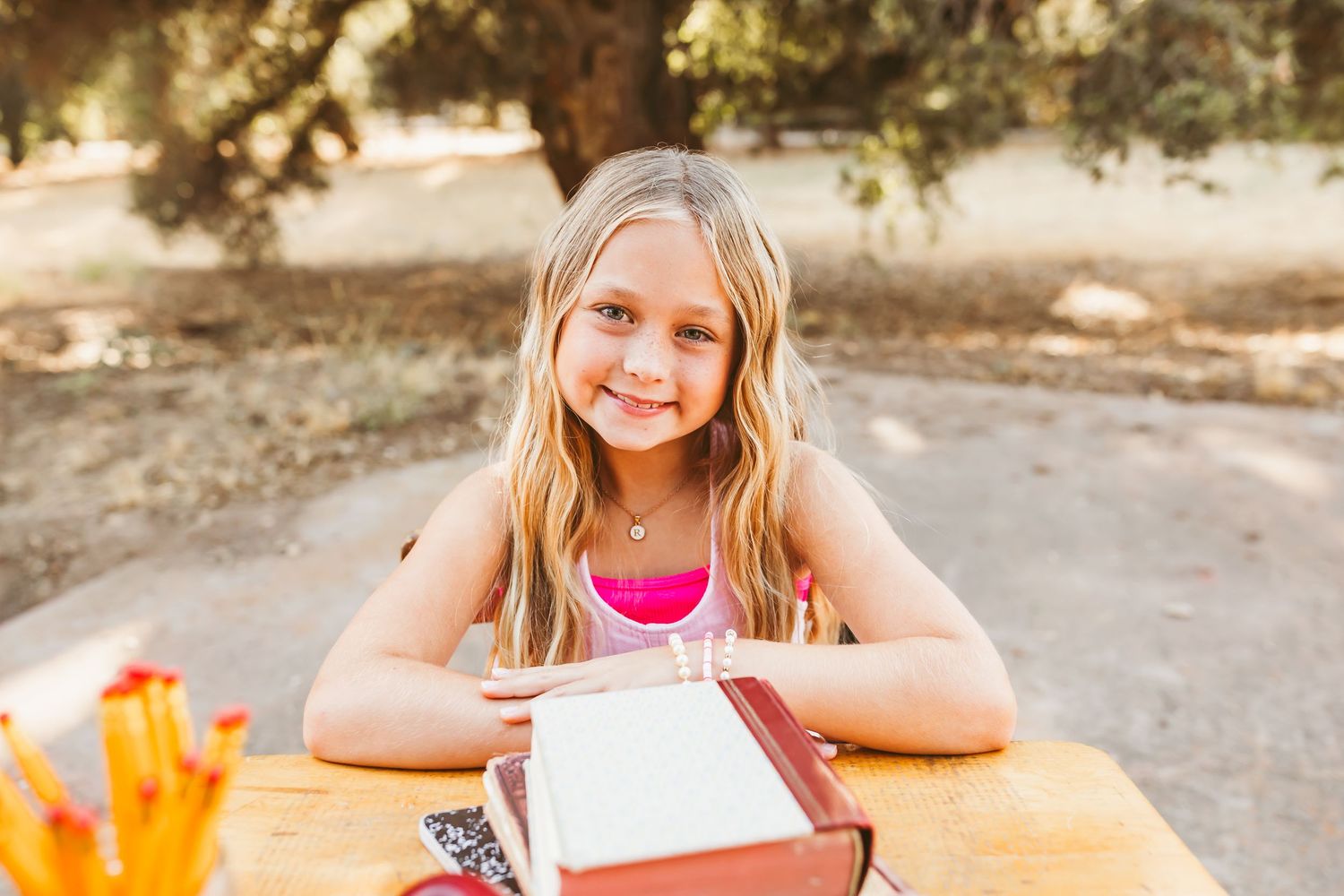 A group of young students sitting at a picnic table outdoors while working on homework assignments together.