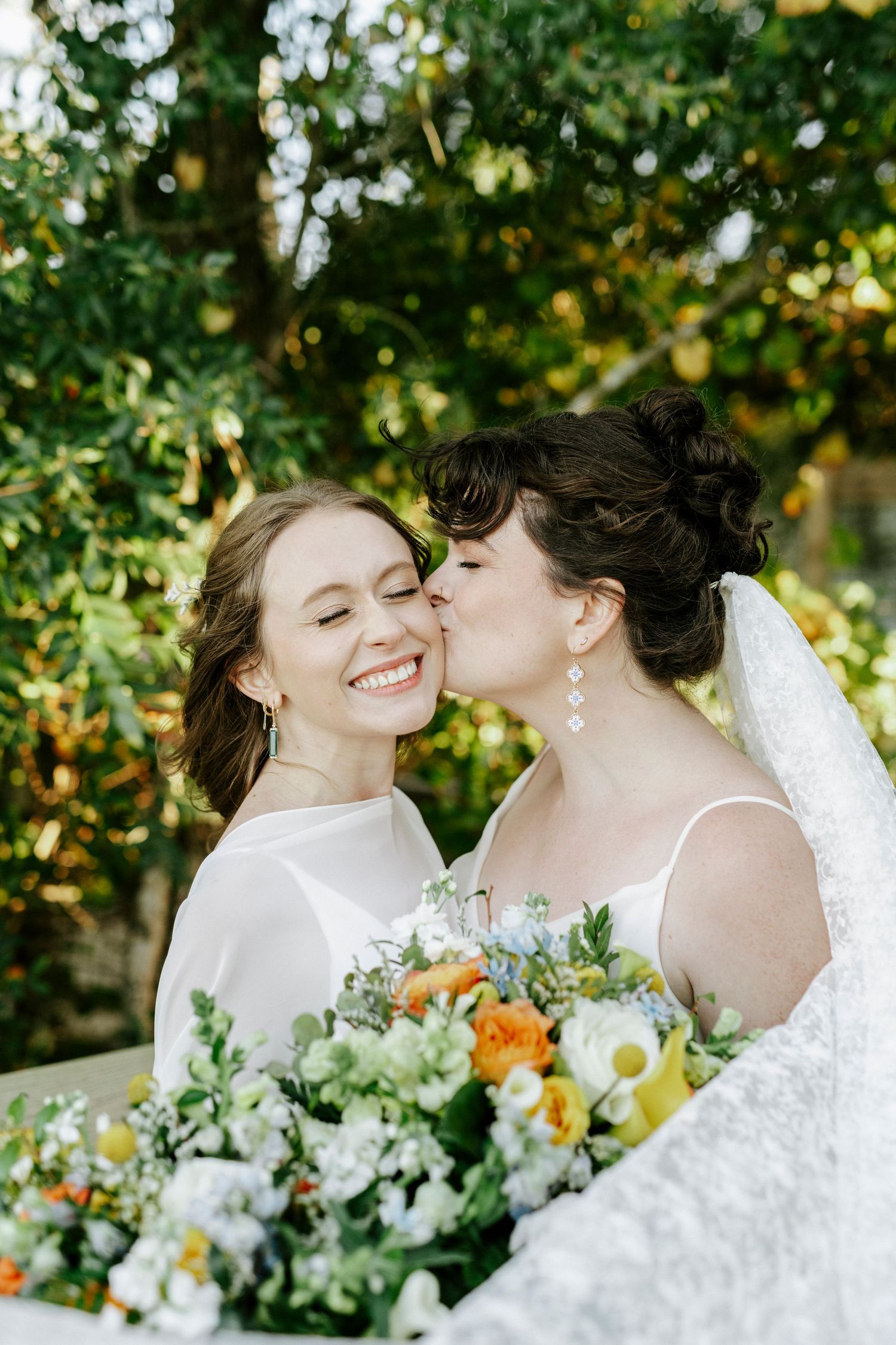 A romantic wedding moment captured in nature with beautiful orange and white floral bouquets.