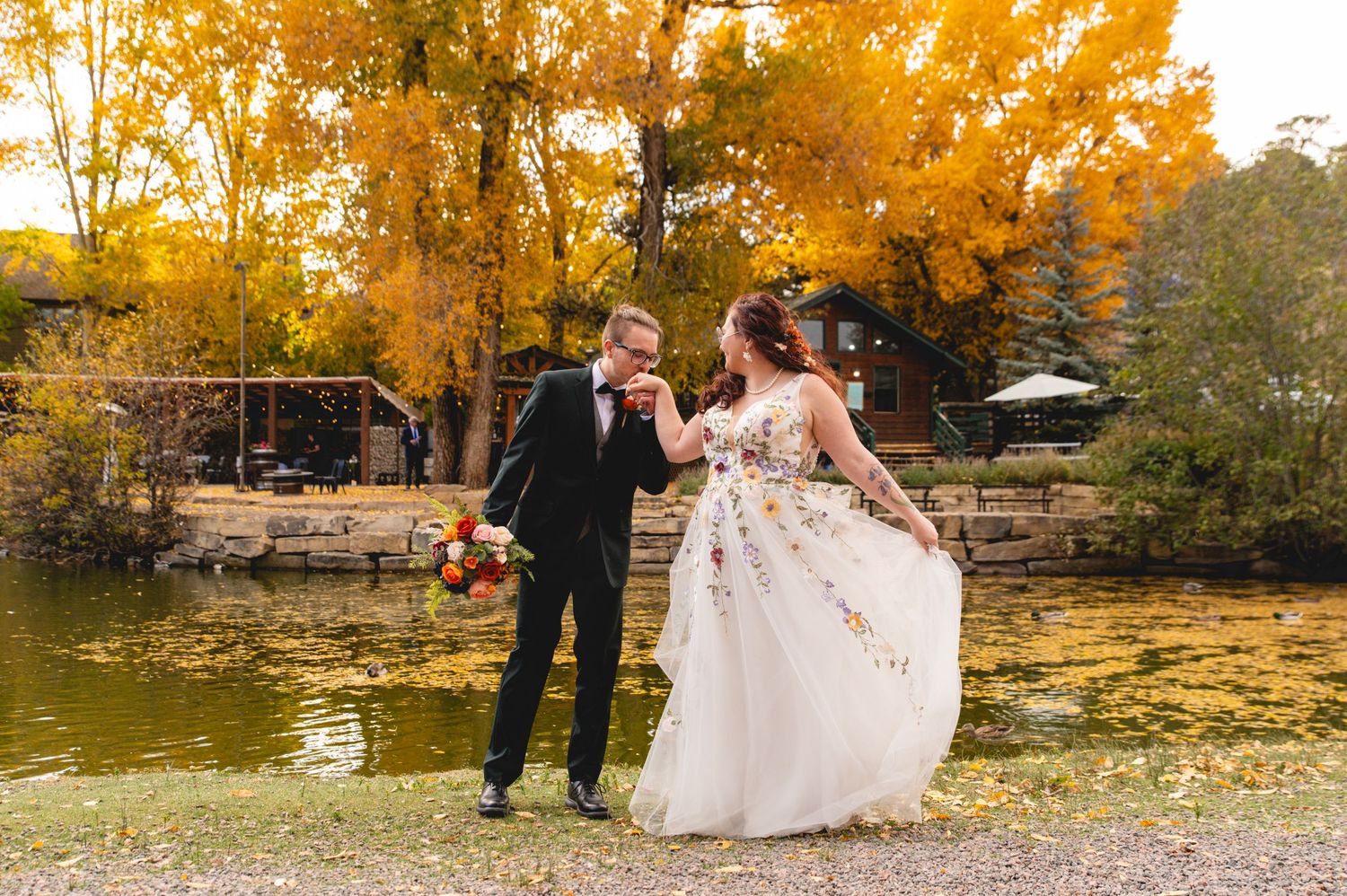 Couple walks together on autumn path surrounded by vibrant golden foliage during outdoor fall photo session.