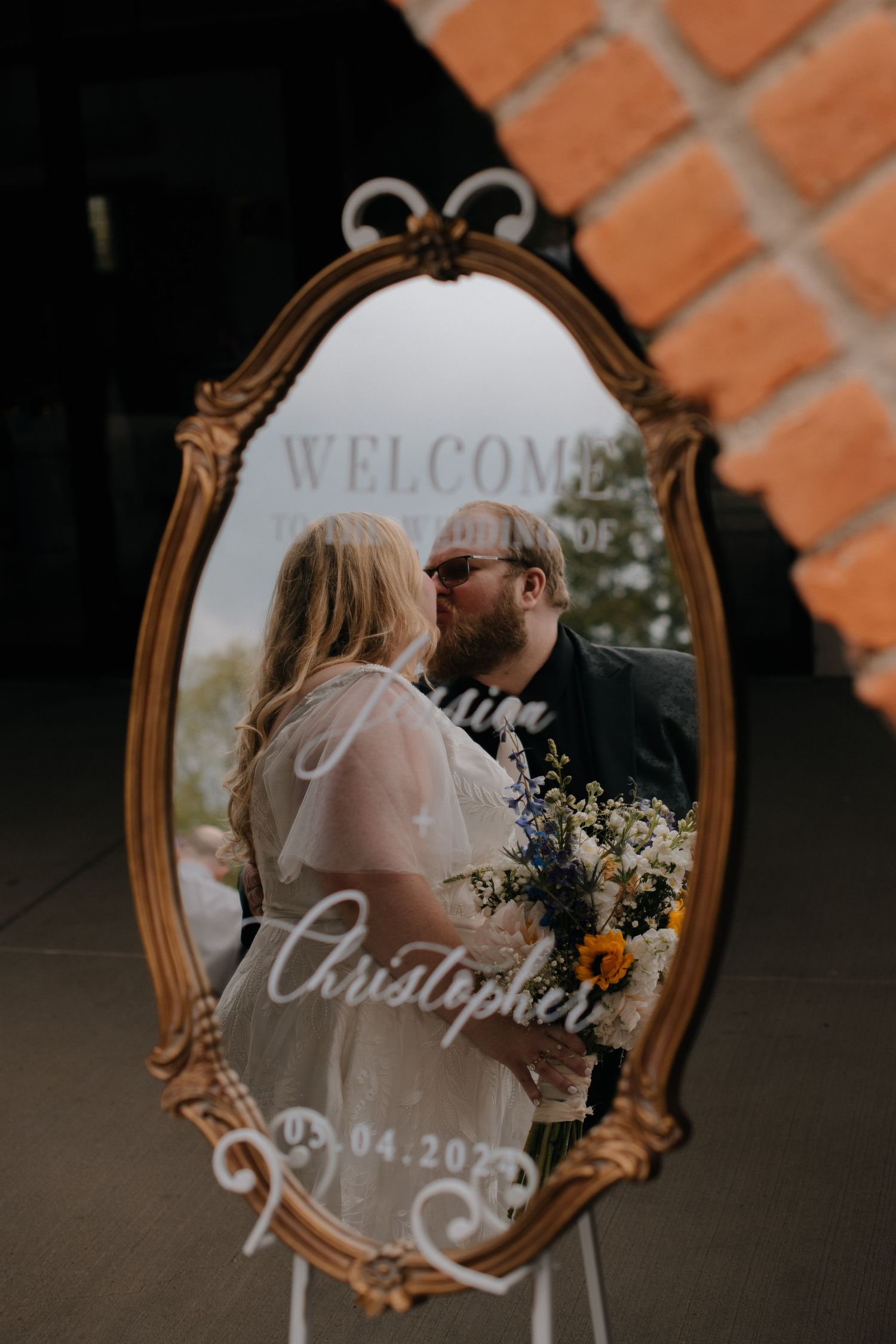 An ornate gold mirror displays a welcome message with wedding details and romantic reflection.